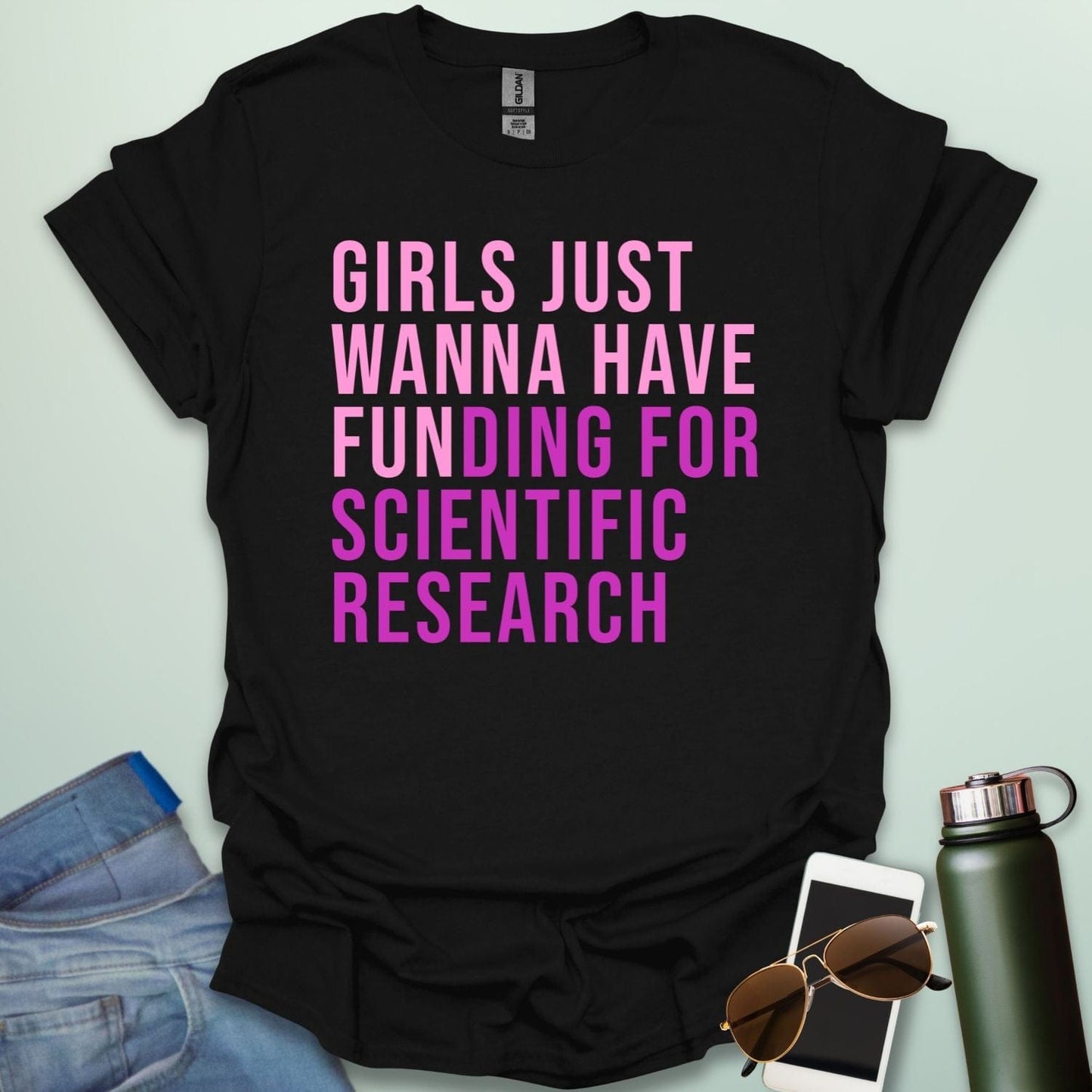 A black t-shirt with the phrase 'Girls just wanna have funding for scientific research' in a bold, pink sans-serif font.