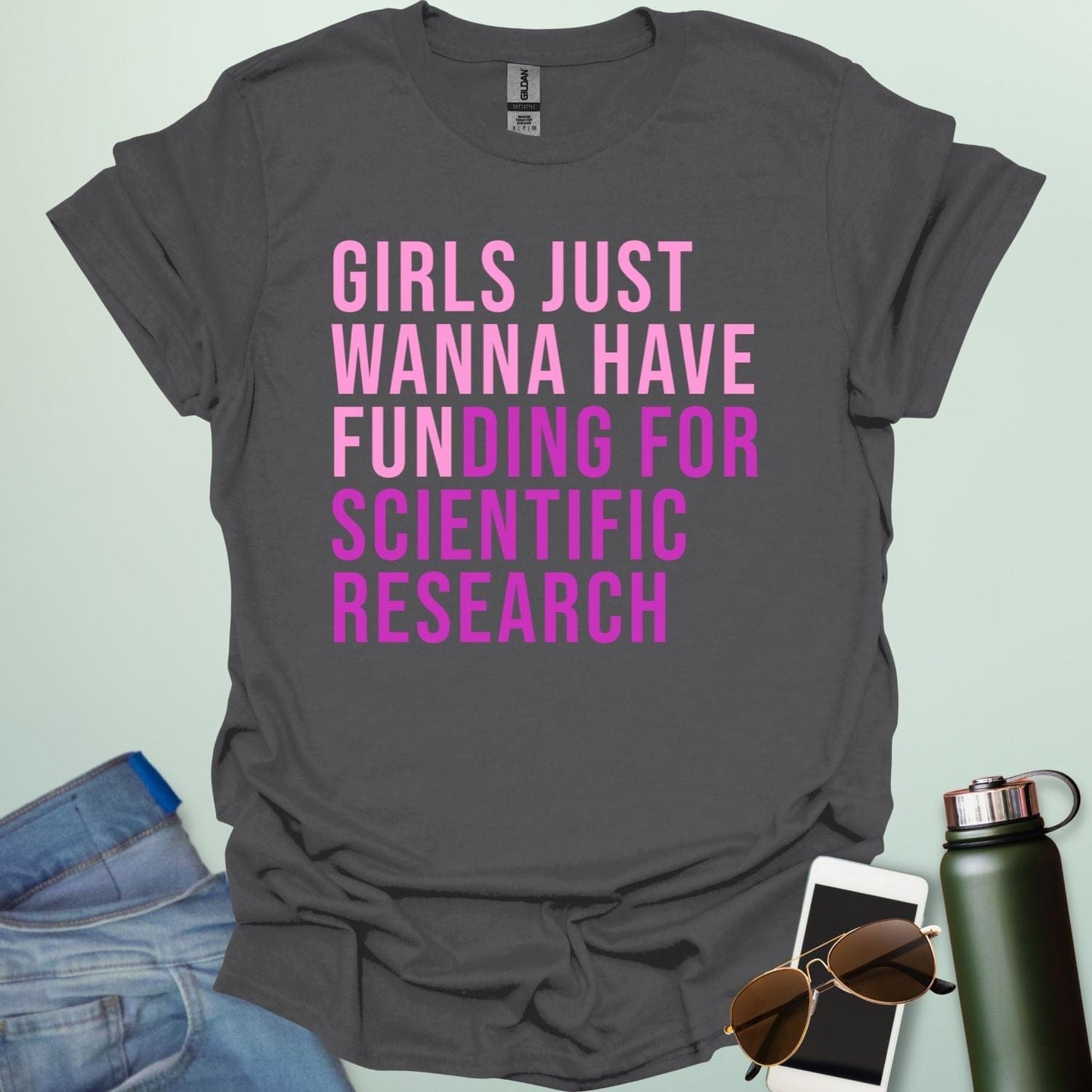 A charcoal grey t-shirt with the phrase 'Girls just wanna have funding for scientific research' in a bold, pink sans-serif font.