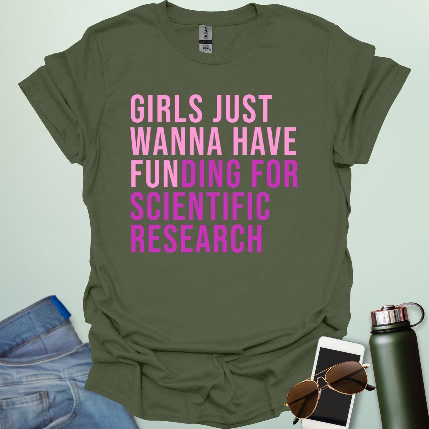 A military green t-shirt with the phrase 'Girls just wanna have funding for scientific research' in a bold, pink sans-serif font.