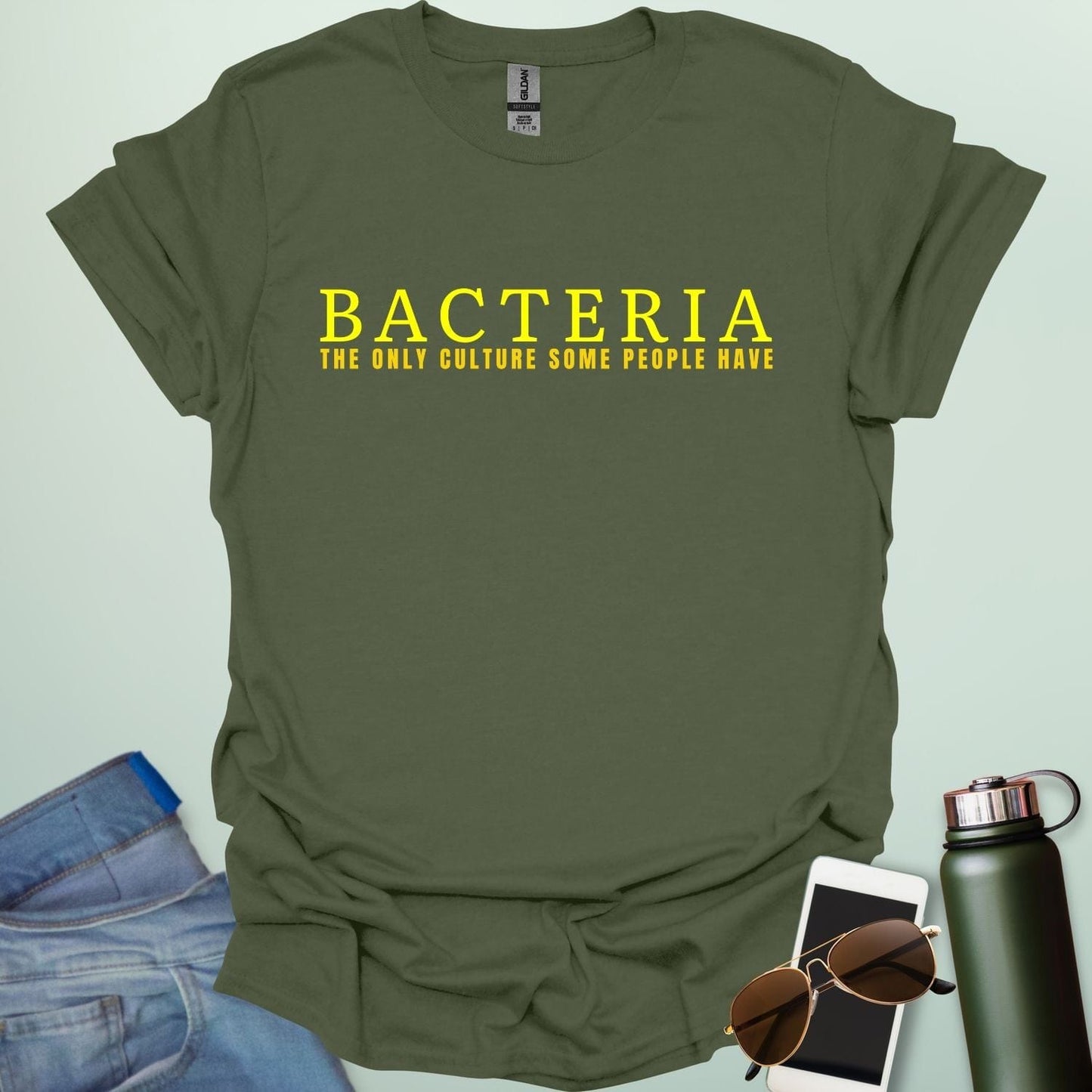 A military green t-shirt with the text 'BACTERIA THE ONLY CULTURE SOME PEOPLE HAVE' in yellow, bold font.