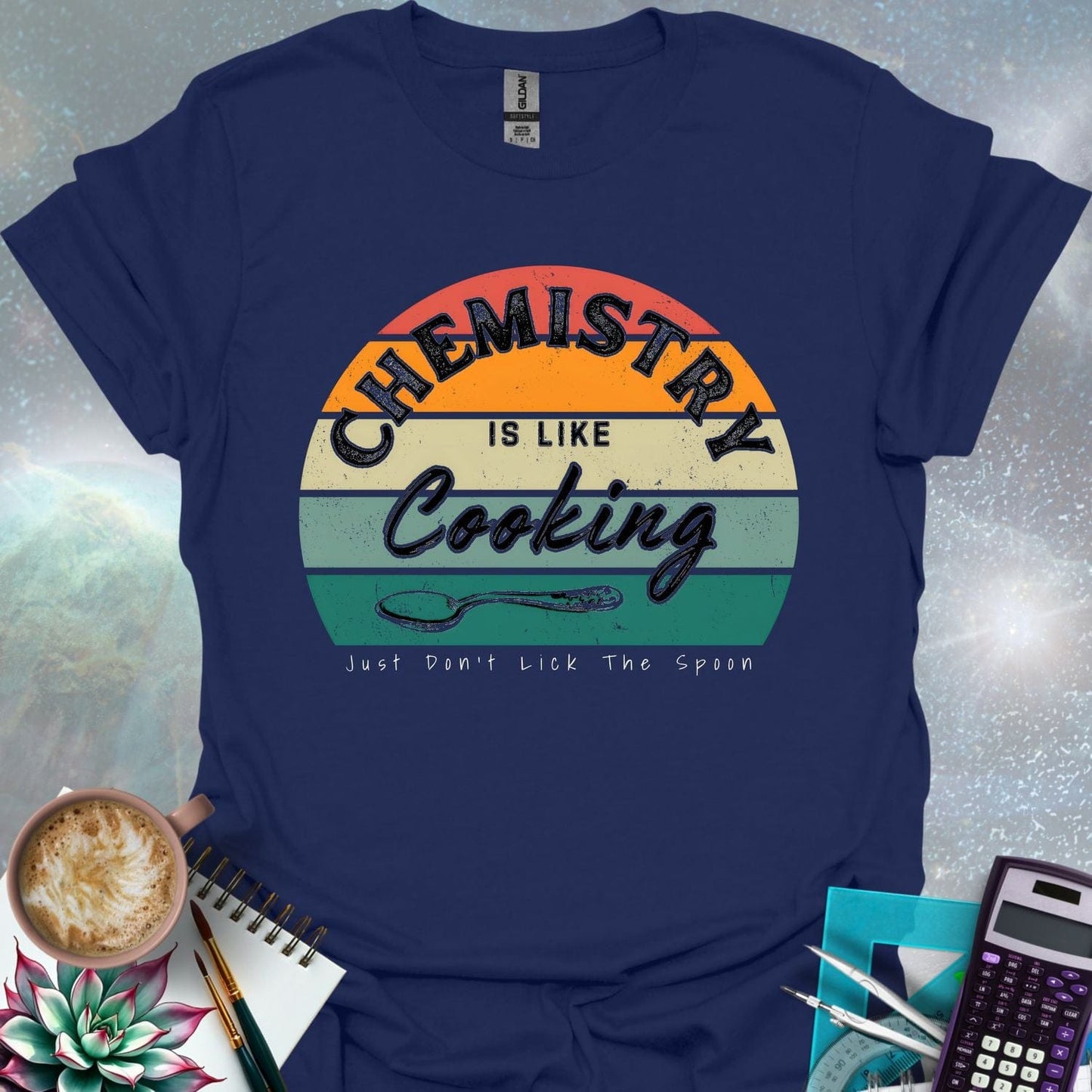 The text 'Chemistry is like Cooking - Just don't lick the spoon' in a distressed, grunge font, with a spoon graphic and a retro-style sunset background.