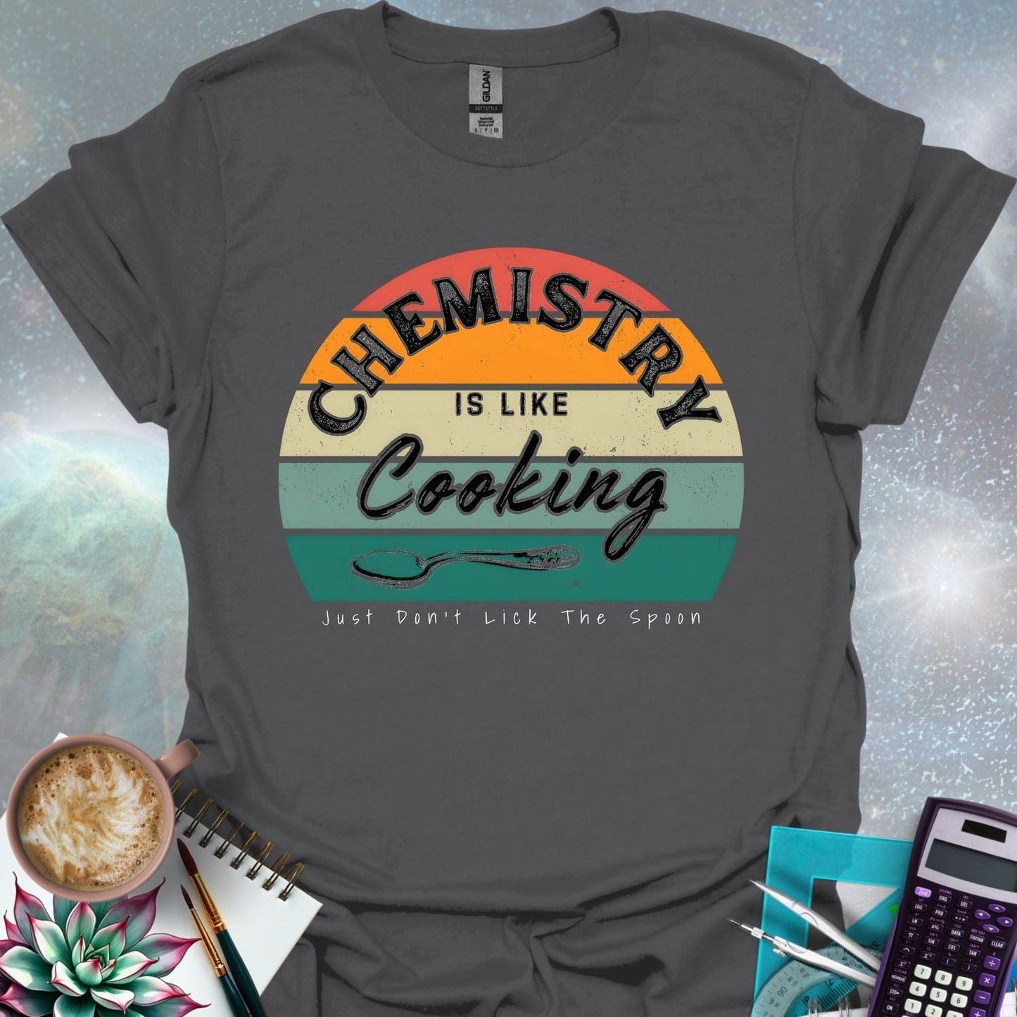 The text 'Chemistry is like Cooking - Just don't lick the spoon' in a distressed, grunge font, with a spoon graphic and a retro-style sunset background.