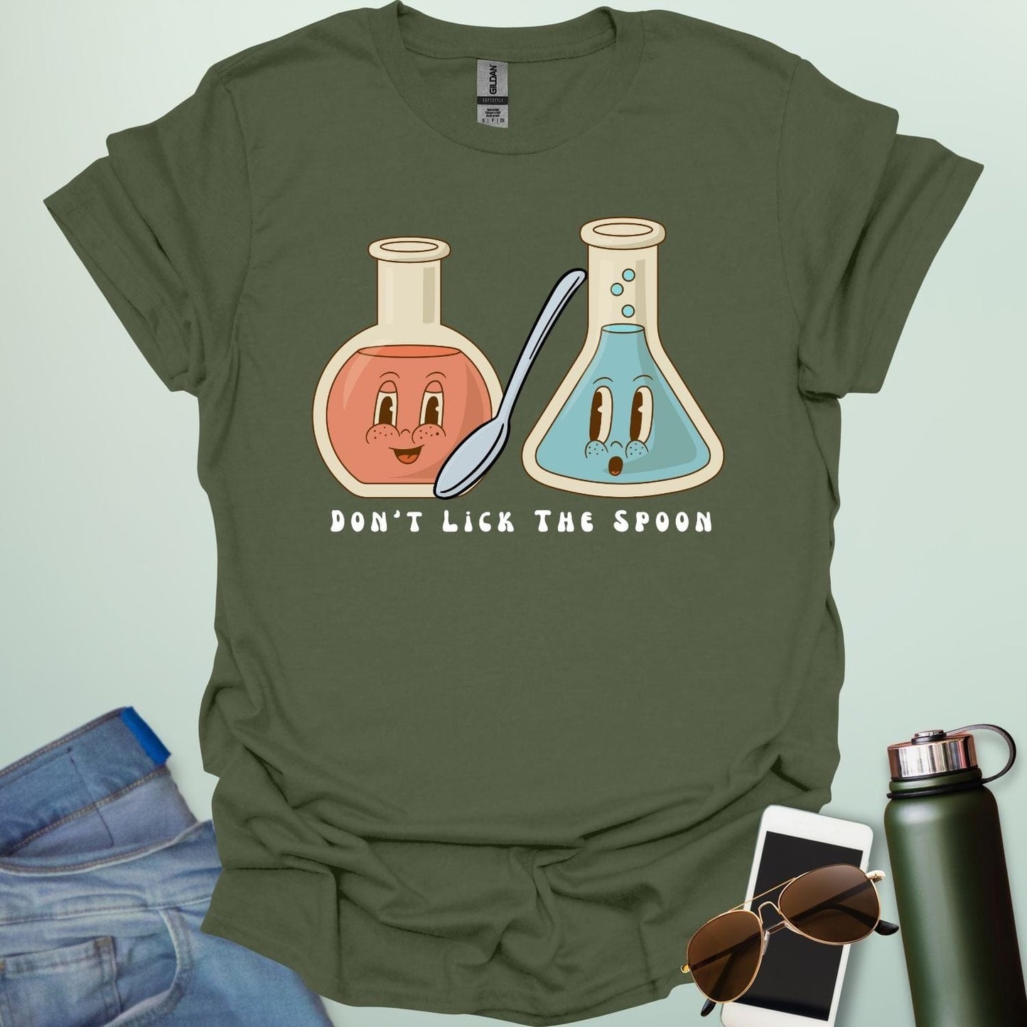 A military green t-shirt with a cartoon illustration of two lab flasks and a spoon, with the text 'Don't Lick The Spoon.
