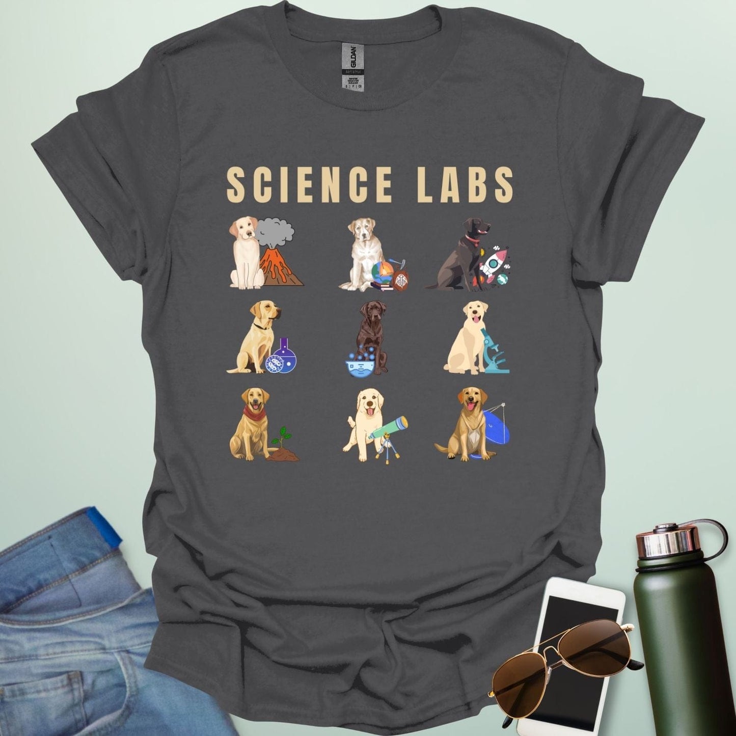 A charcoal grey t-shirt with the text 'SCIENCE LABS' and a grid of nine illustrations of Labrador Retrievers in various science-themed scenarios.