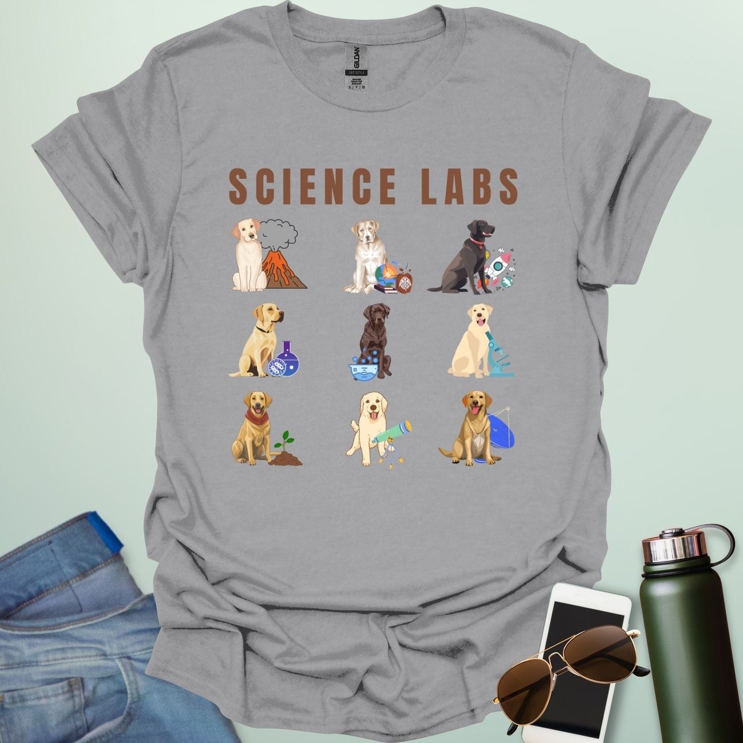 A sport grey t-shirt with the text 'SCIENCE LABS' and a grid of nine illustrations of Labrador Retrievers in various science-themed scenarios.
