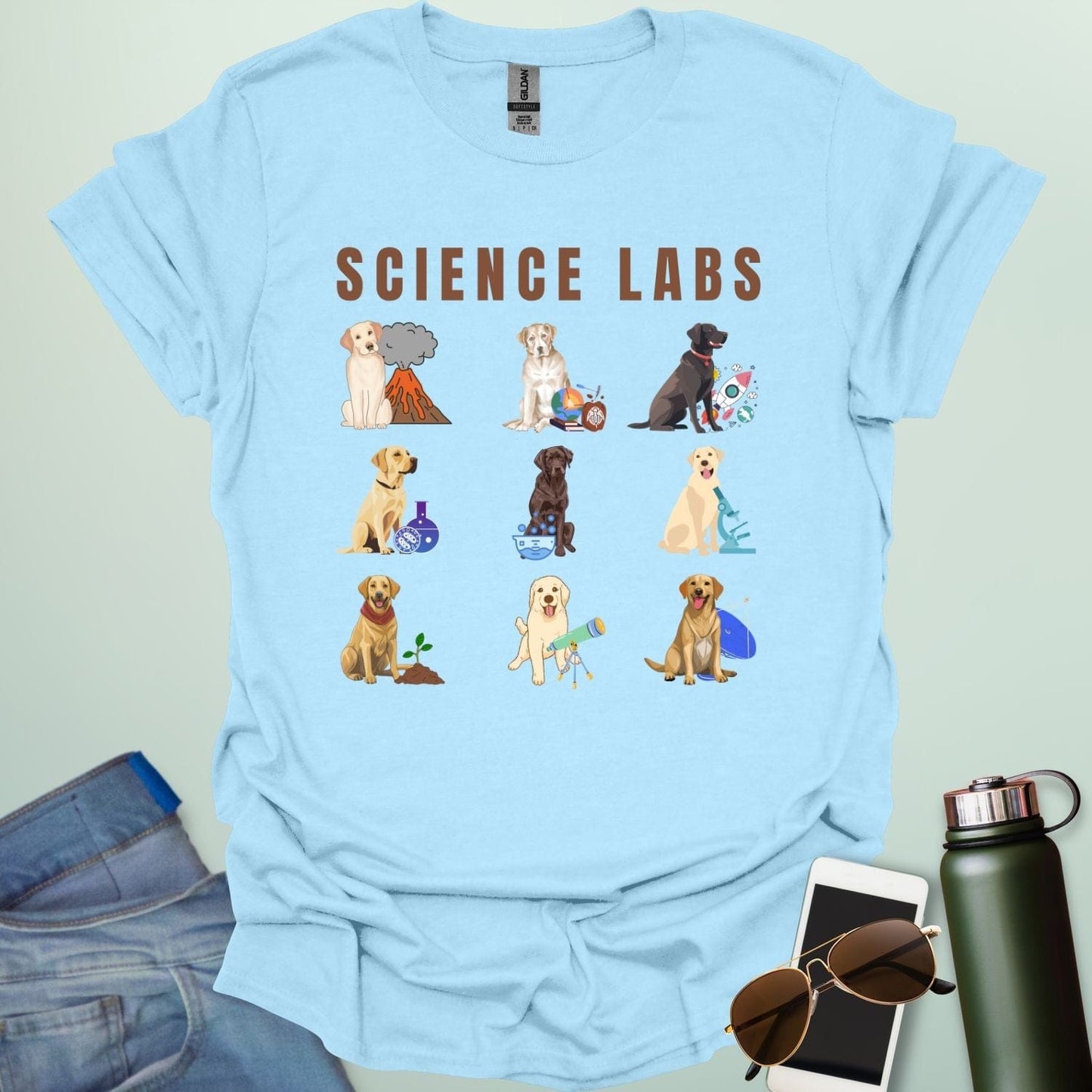 A light blue t-shirt with the text 'SCIENCE LABS' and a grid of nine illustrations of Labrador Retrievers in various science-themed scenarios.