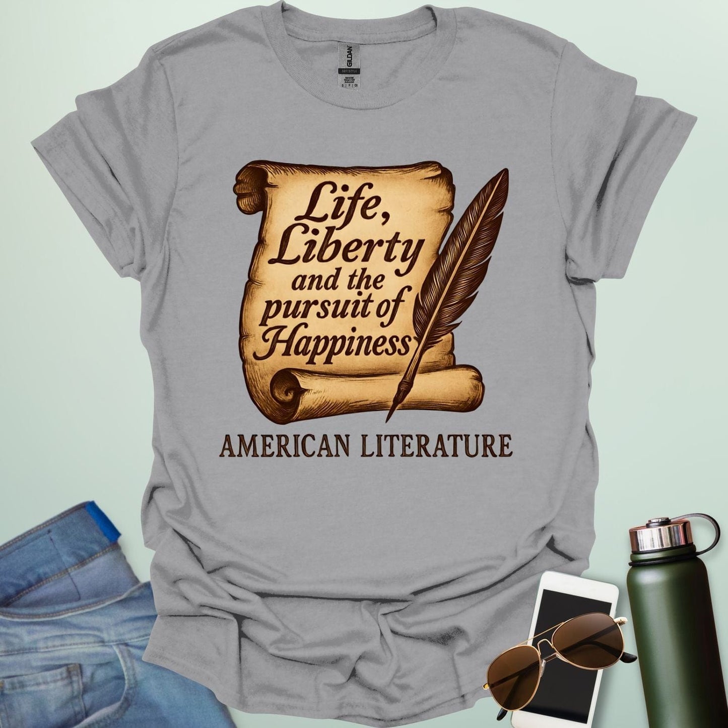 A sport grey t-shirt with a vintage-style scroll and quill pen, and the text 'Life, Liberty and the pursuit of Happiness' and 'American Literature.'