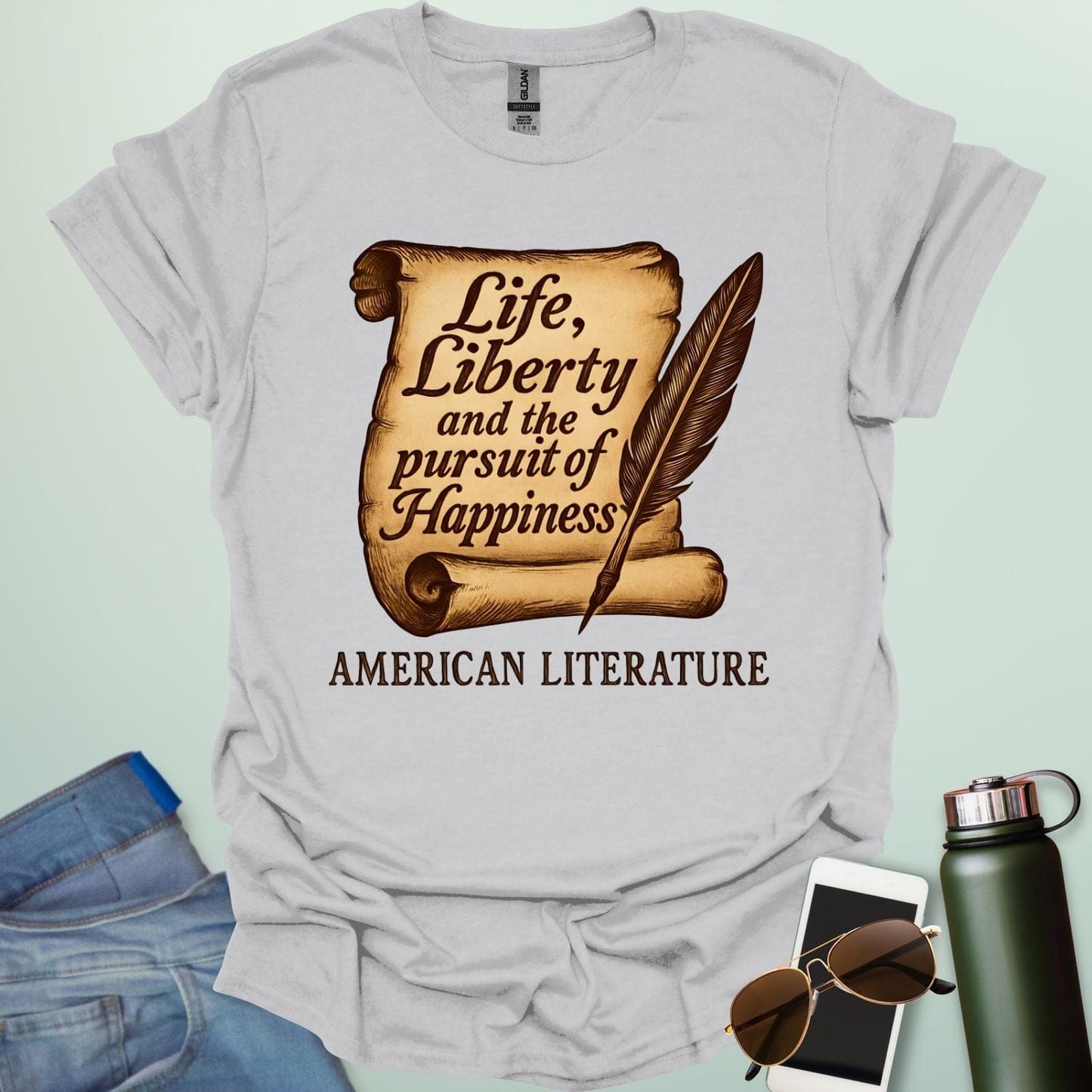An ice grey t-shirt with a vintage-style scroll and quill pen, and the text 'Life, Liberty and the pursuit of Happiness' and 'American Literature.'