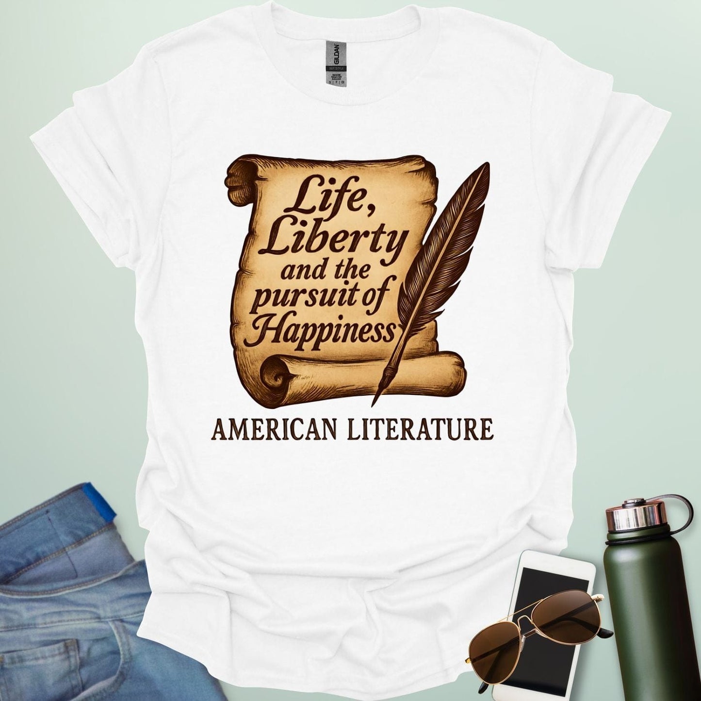 A white t-shirt with a vintage-style scroll and quill pen, and the text 'Life, Liberty and the pursuit of Happiness' and 'American Literature.'