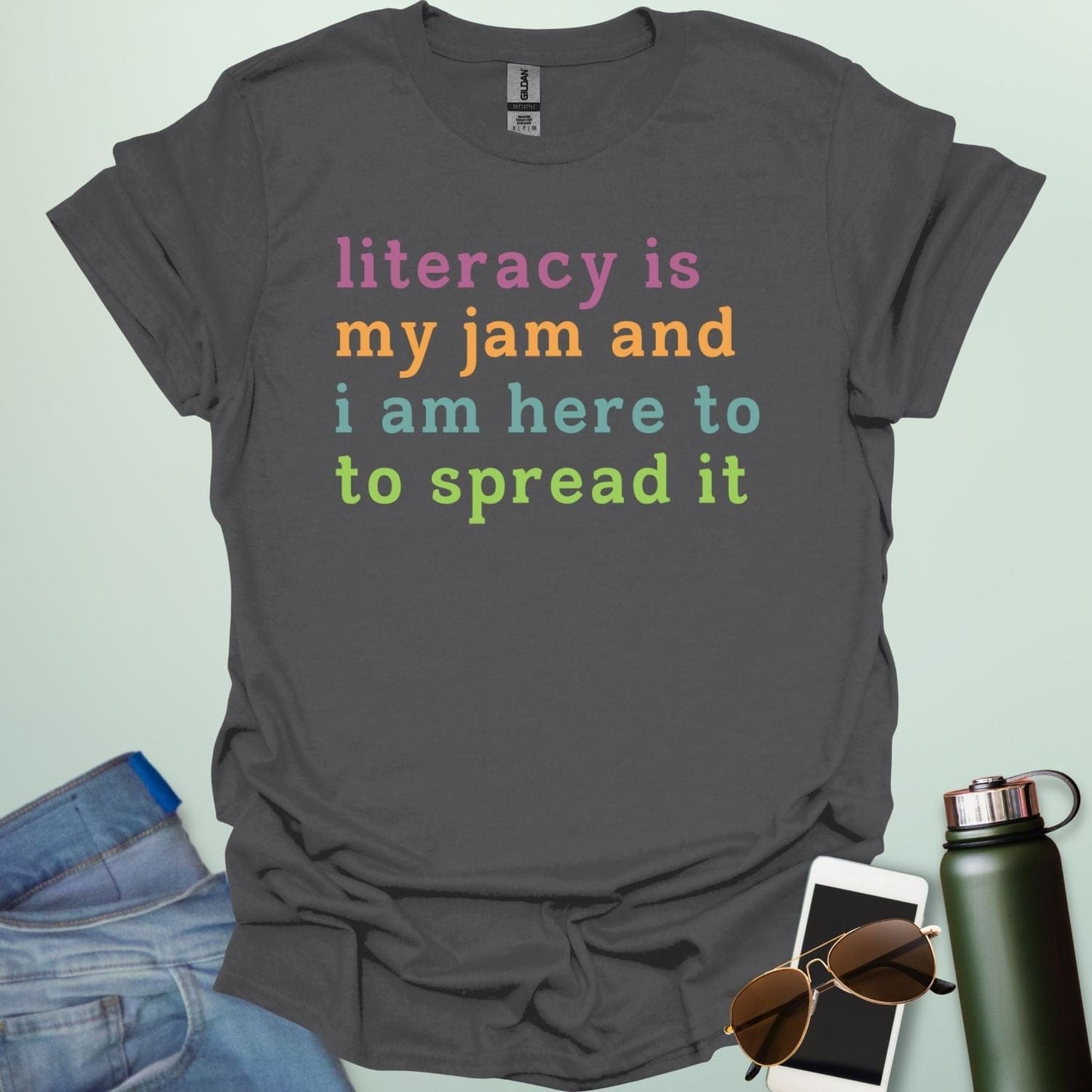 Charcoal gray T-shirt with the text 'literacy is my jam and i'm here to spread it' in colorful, bold lettering.