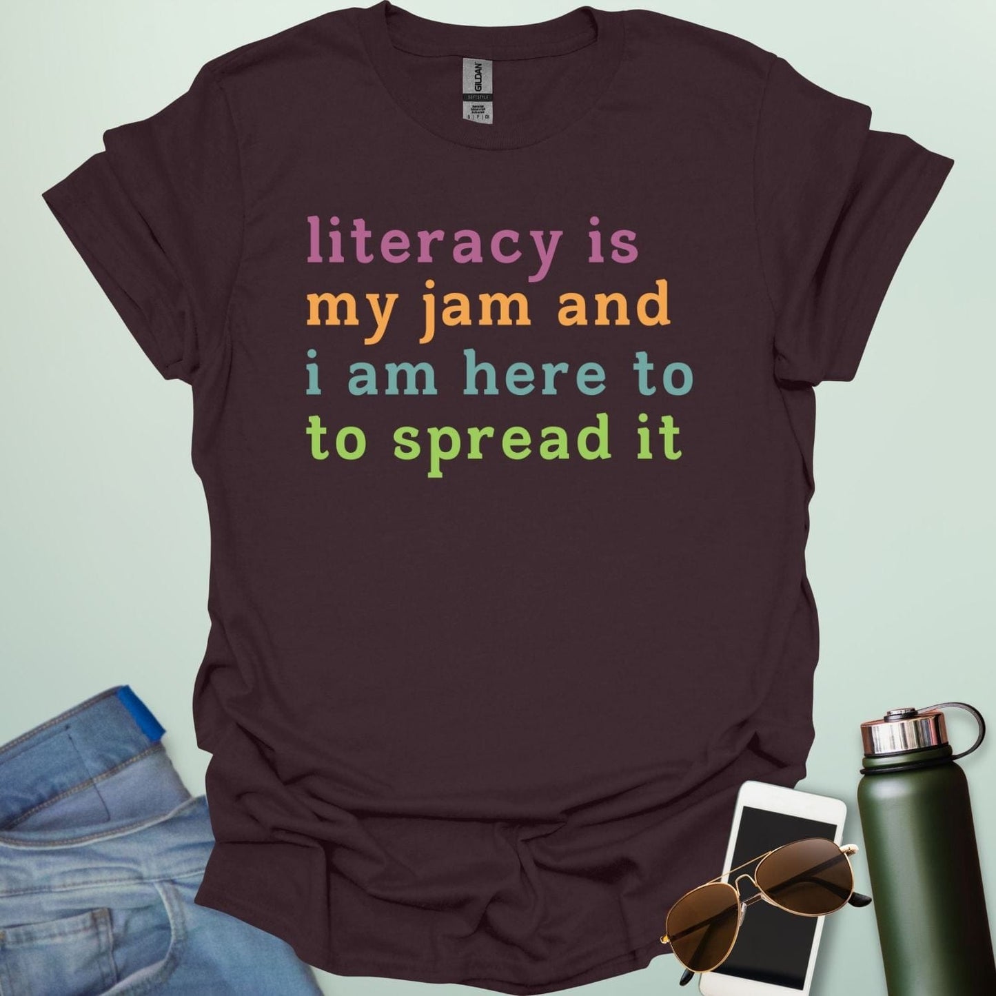 Dark chocolate T-shirt with the text 'literacy is my jam and i'm here to spread it' in colorful, bold lettering.
