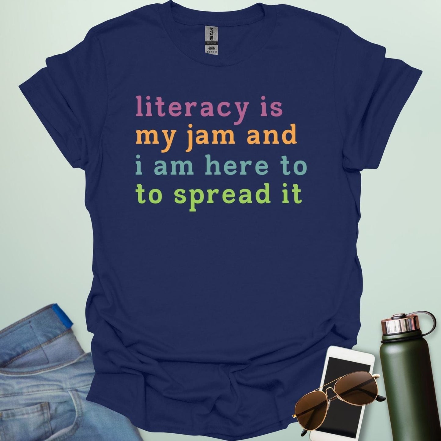 Navy blue T-shirt with the text 'literacy is my jam and i'm here to spread it' in colorful, bold lettering.