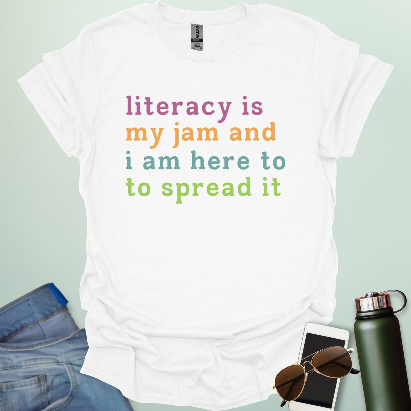 White T-shirt with the text 'literacy is my jam and i'm here to spread it' in colorful, bold lettering.
