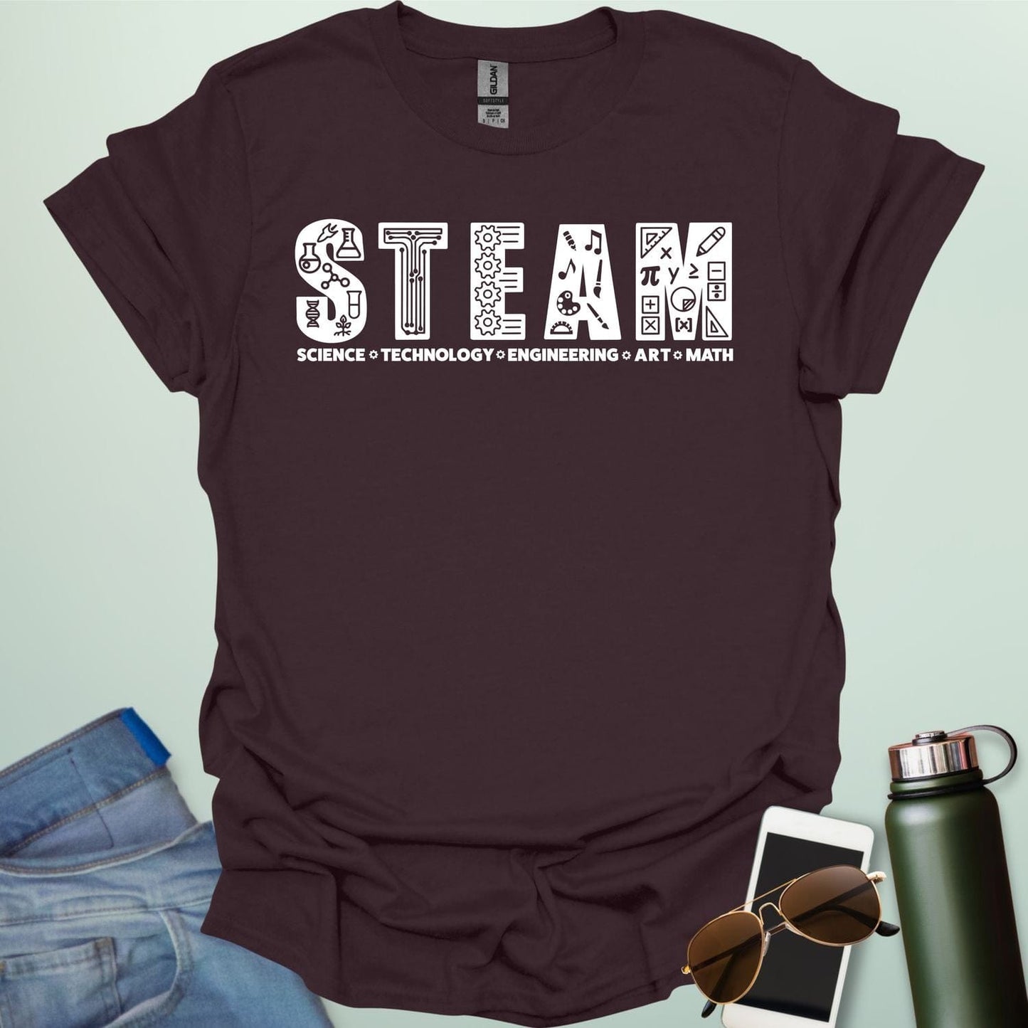 Dark chocolate tee with the word 'STEAM' with each letter filled with related icons, and the words 'SCIENCE TECHNOLOGY ENGINEERING ART MATH' below.