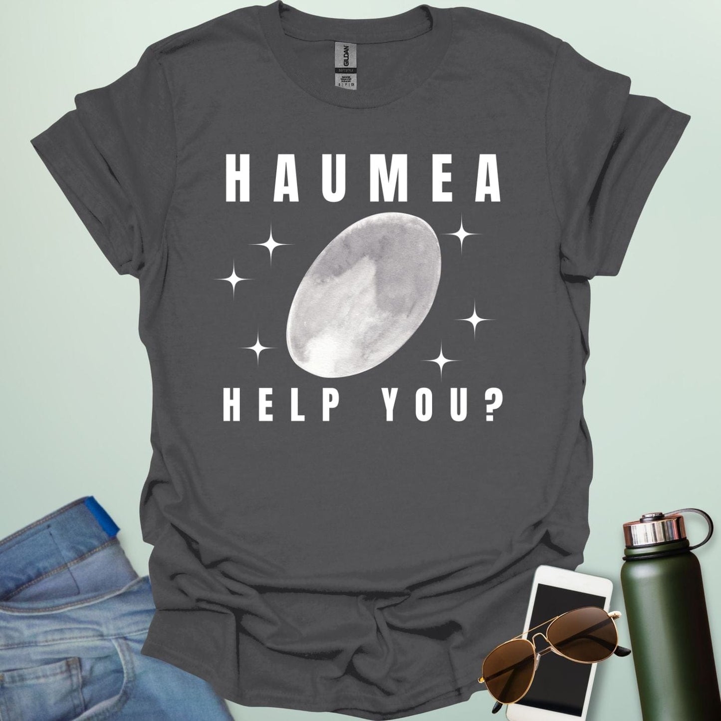 "A charcoal grey t-shirt with a drawing of the dwarf planet Haumea and the text 'HAUMEA HELP YOU?'