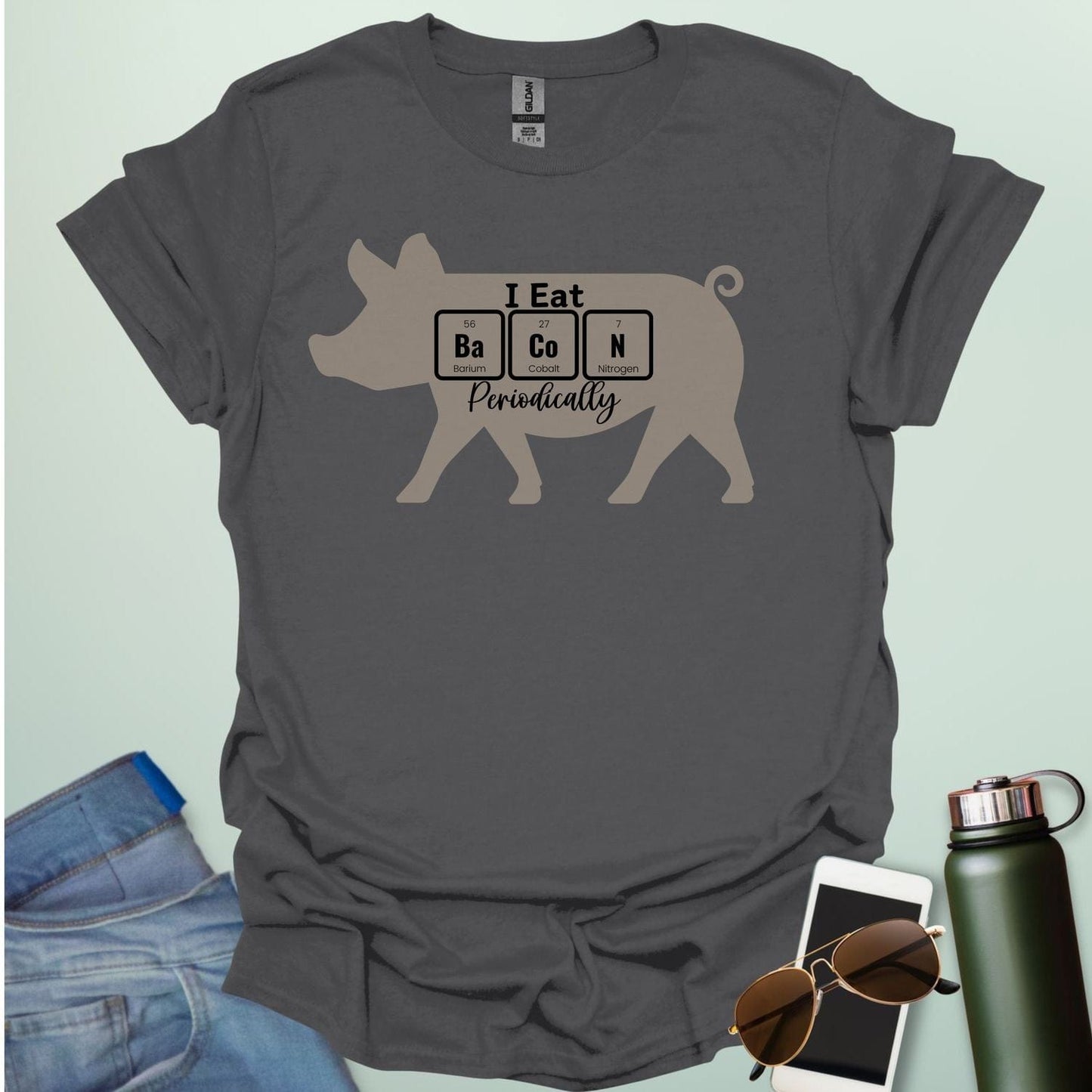 T-shirt design featuring a pig silhouette with the text 'I Eat Bacon Periodically,' where 'Bacon' is spelled using periodic table element symbols.