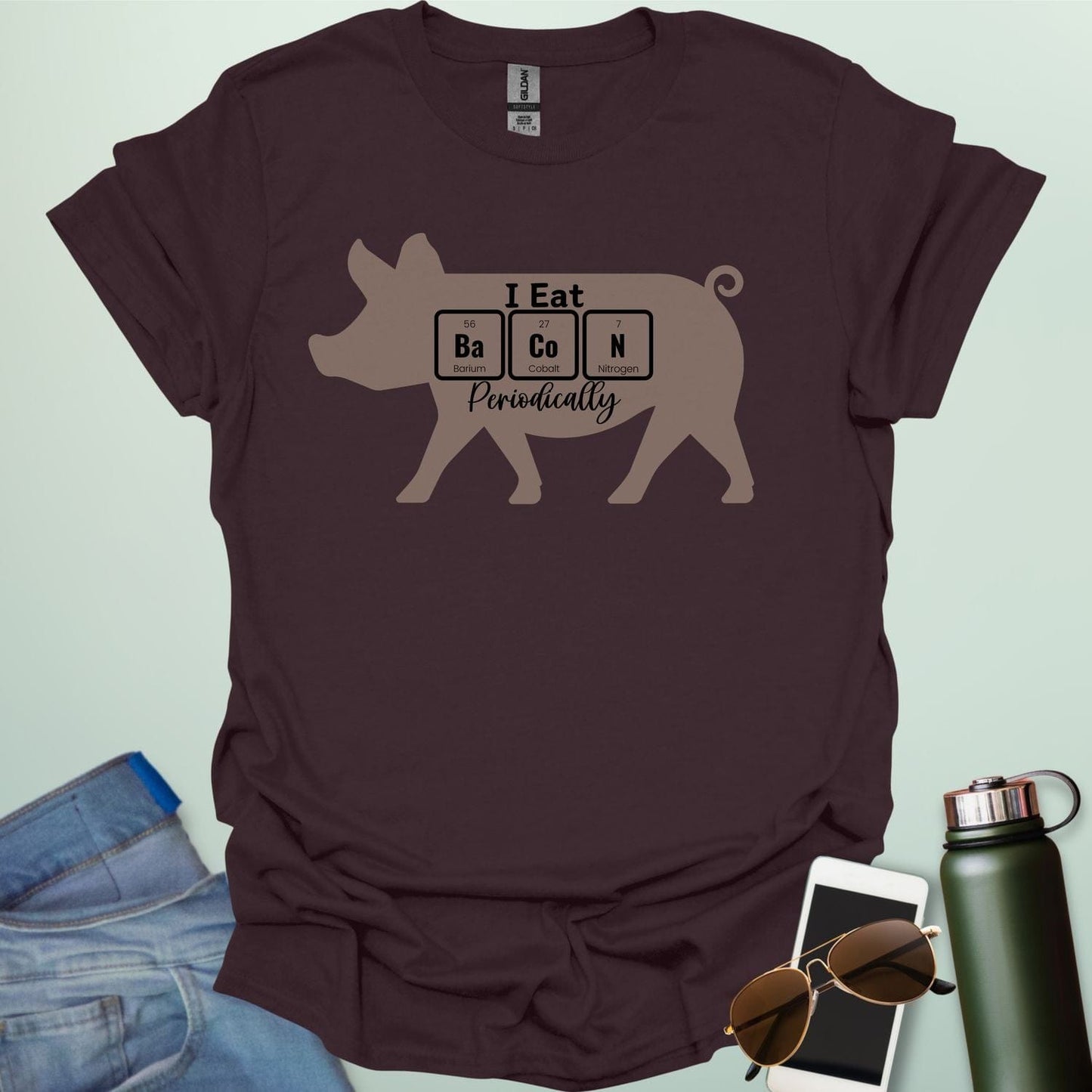 T-shirt design featuring a pig silhouette with the text 'I Eat Bacon Periodically,' where 'Bacon' is spelled using periodic table element symbols.
