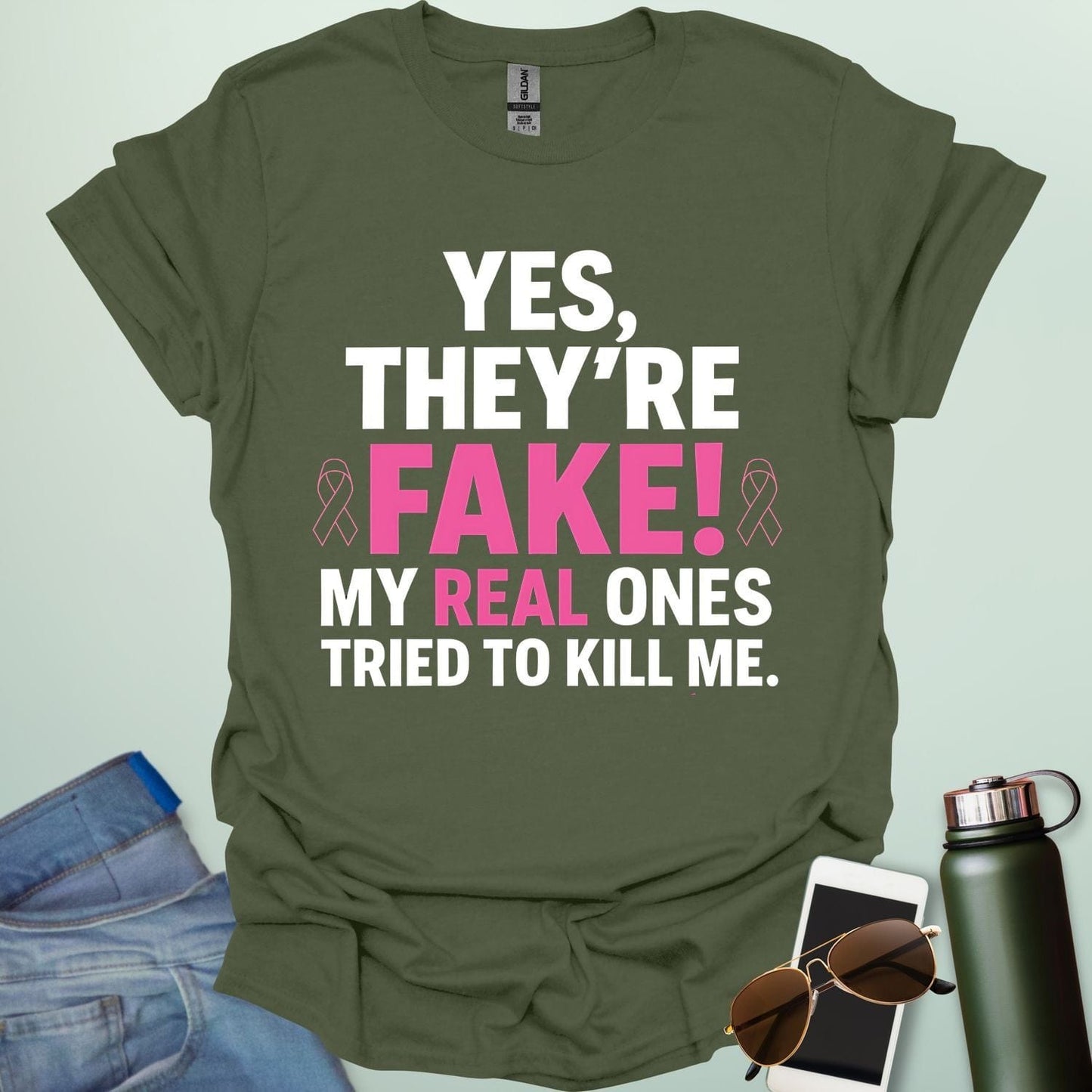 ‘Yes, They’re Fake — My Real Ones Tried to Kill Me’ t-shirt design with bold typography — breast cancer awareness & survivorship statement shirt.