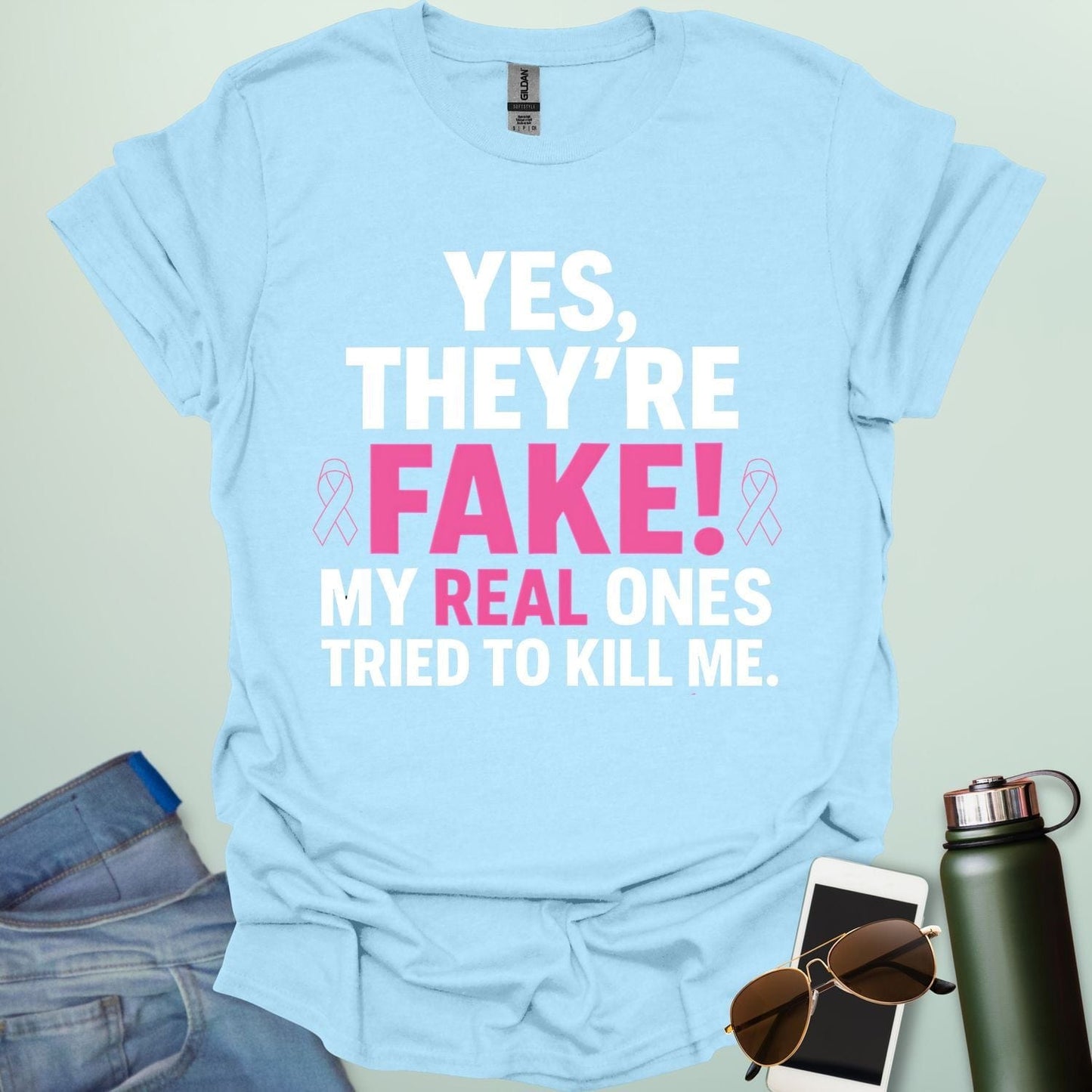 ‘Yes, They’re Fake — My Real Ones Tried to Kill Me’ t-shirt design with bold typography — breast cancer awareness & survivorship statement shirt.