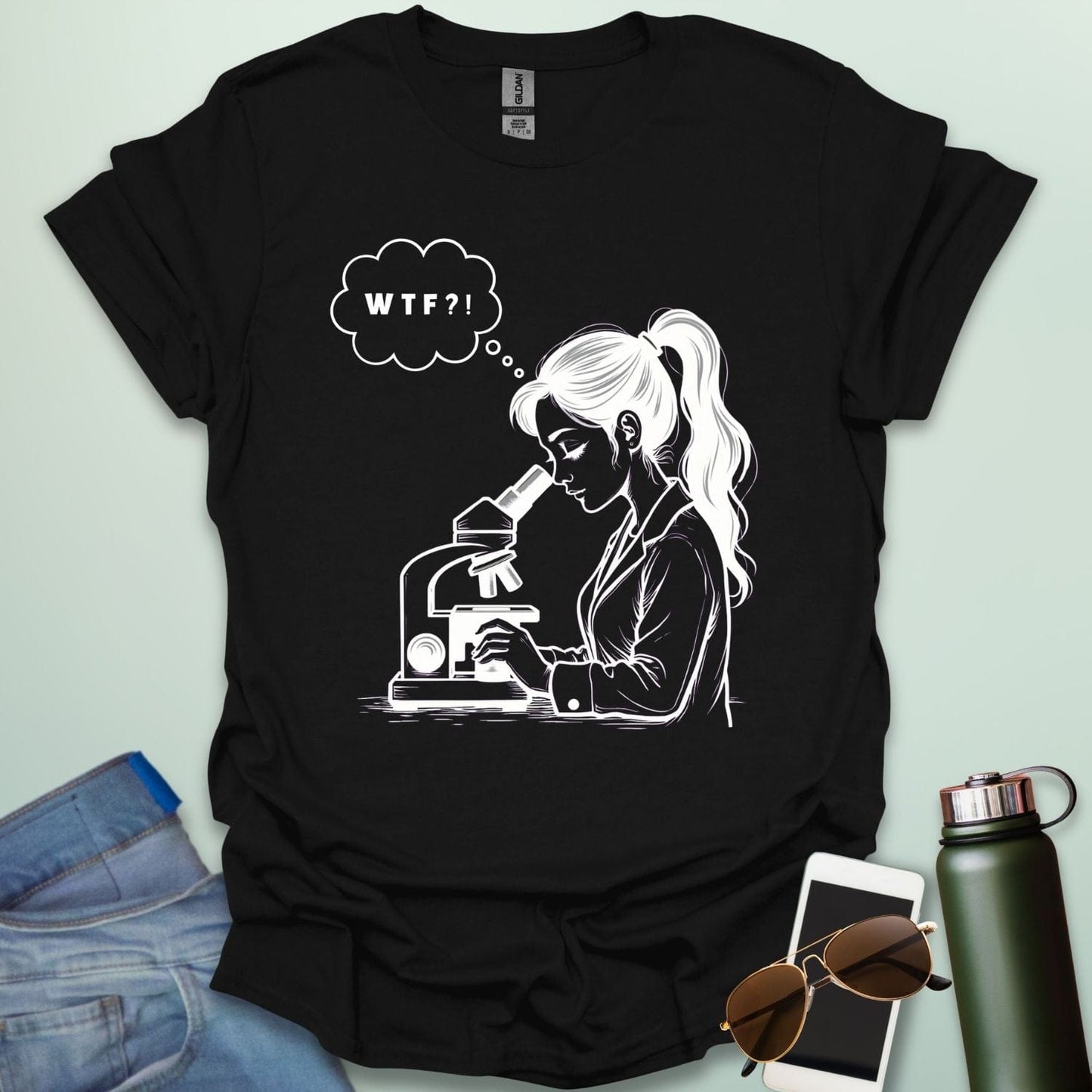 A funny t-shirt for scientists with a line drawing of a woman looking through a microscope and a thought bubble with the text 'WTF?!'