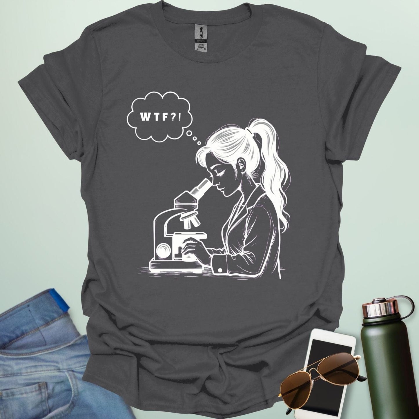 A funny t-shirt for scientists with a line drawing of a woman looking through a microscope and a thought bubble with the text 'WTF?!'