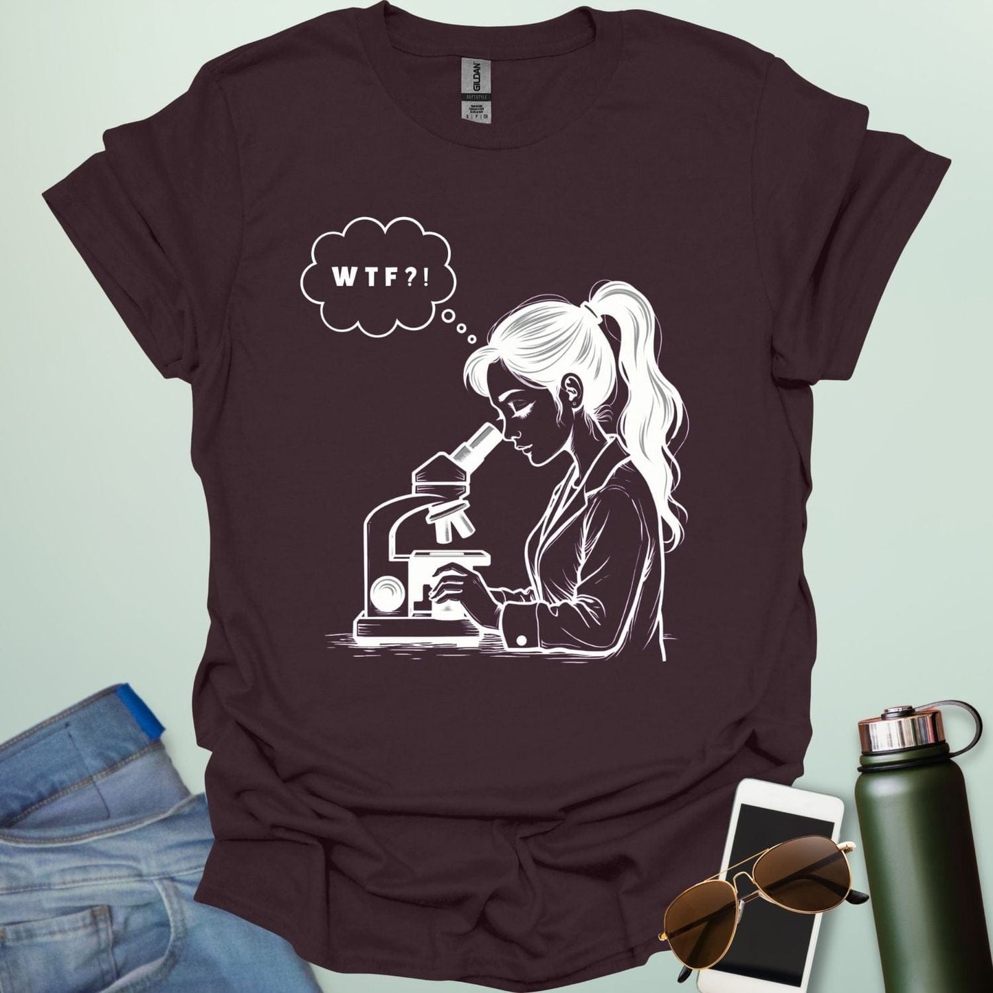 A funny t-shirt for scientists with a line drawing of a woman looking through a microscope and a thought bubble with the text 'WTF?!'