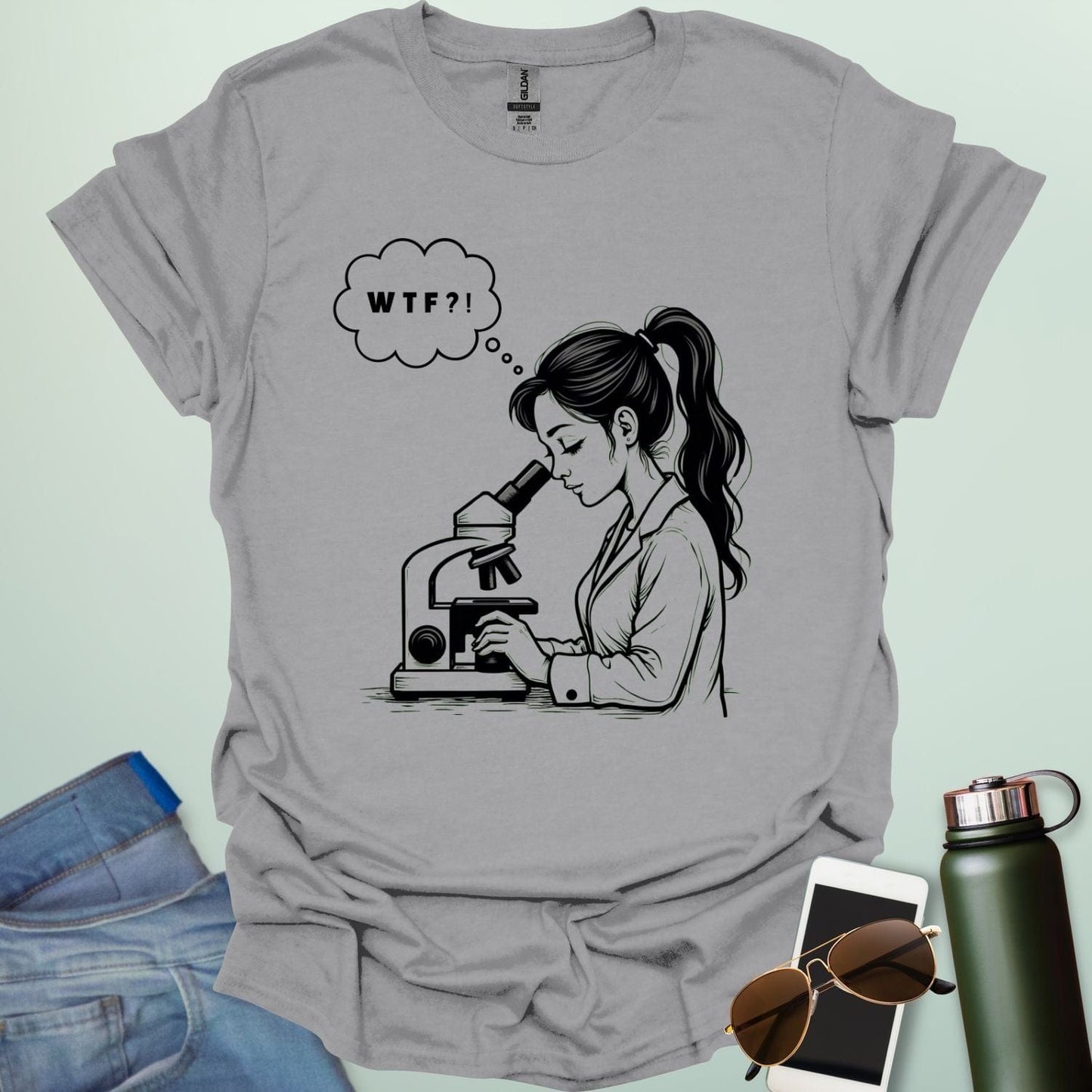 A funny t-shirt for scientists with a line drawing of a woman looking through a microscope and a thought bubble with the text 'WTF?!'