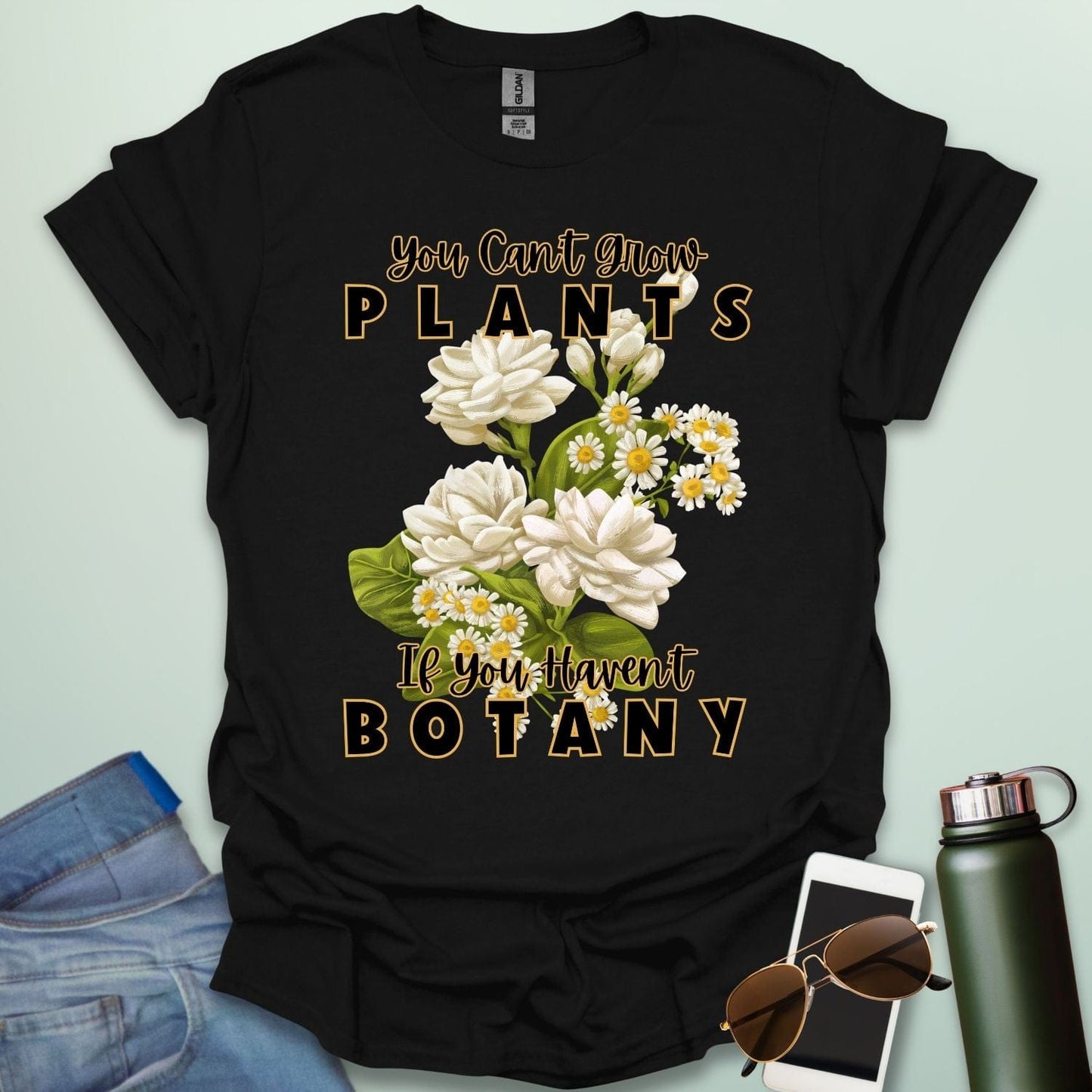 A charming t-shirt with a floral design and the text 'You Can't Grow Plants If You Haven't Botany,' a witty pun for botanists and gardeners.