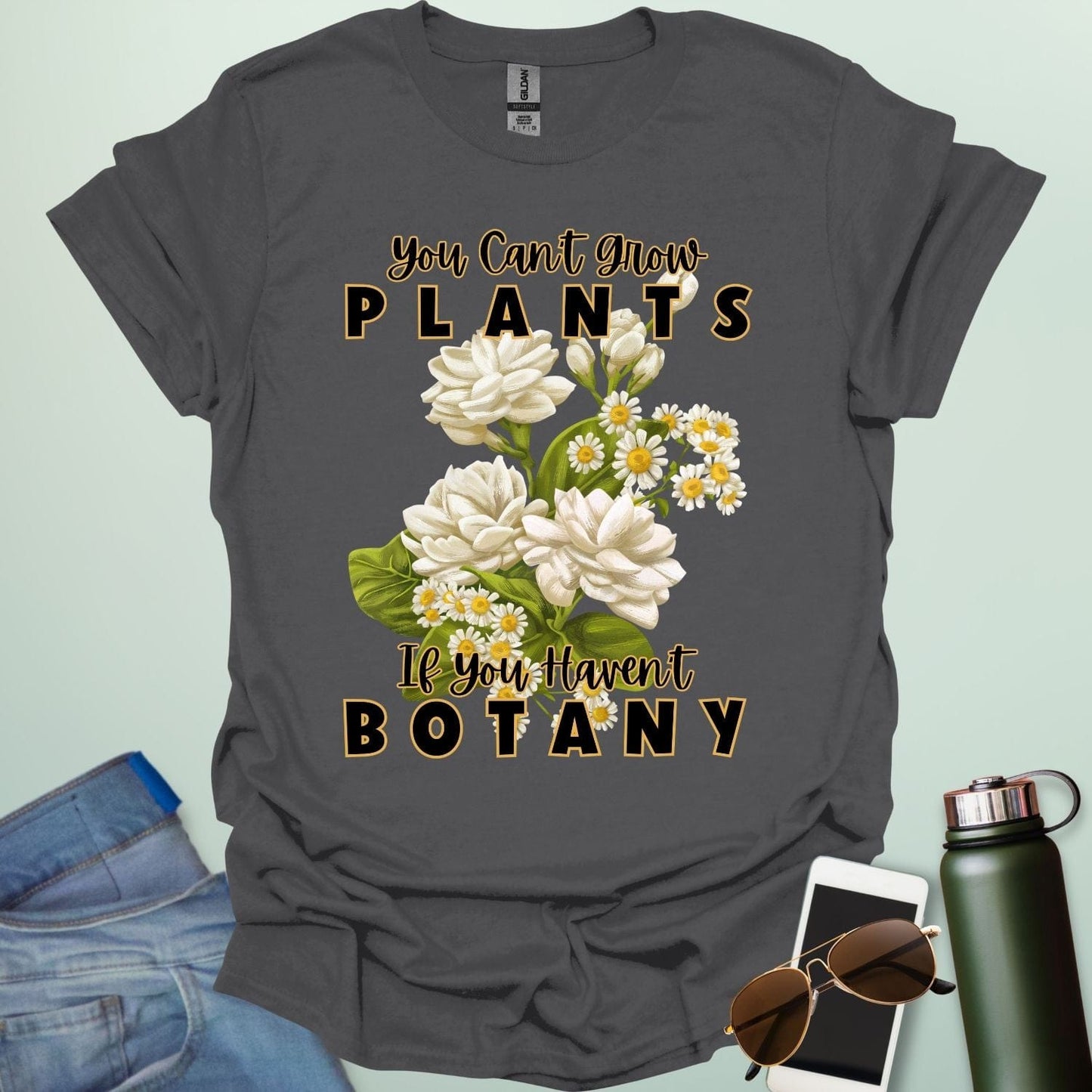 A charming t-shirt with a floral design and the text 'You Can't Grow Plants If You Haven't Botany,' a witty pun for botanists and gardeners.