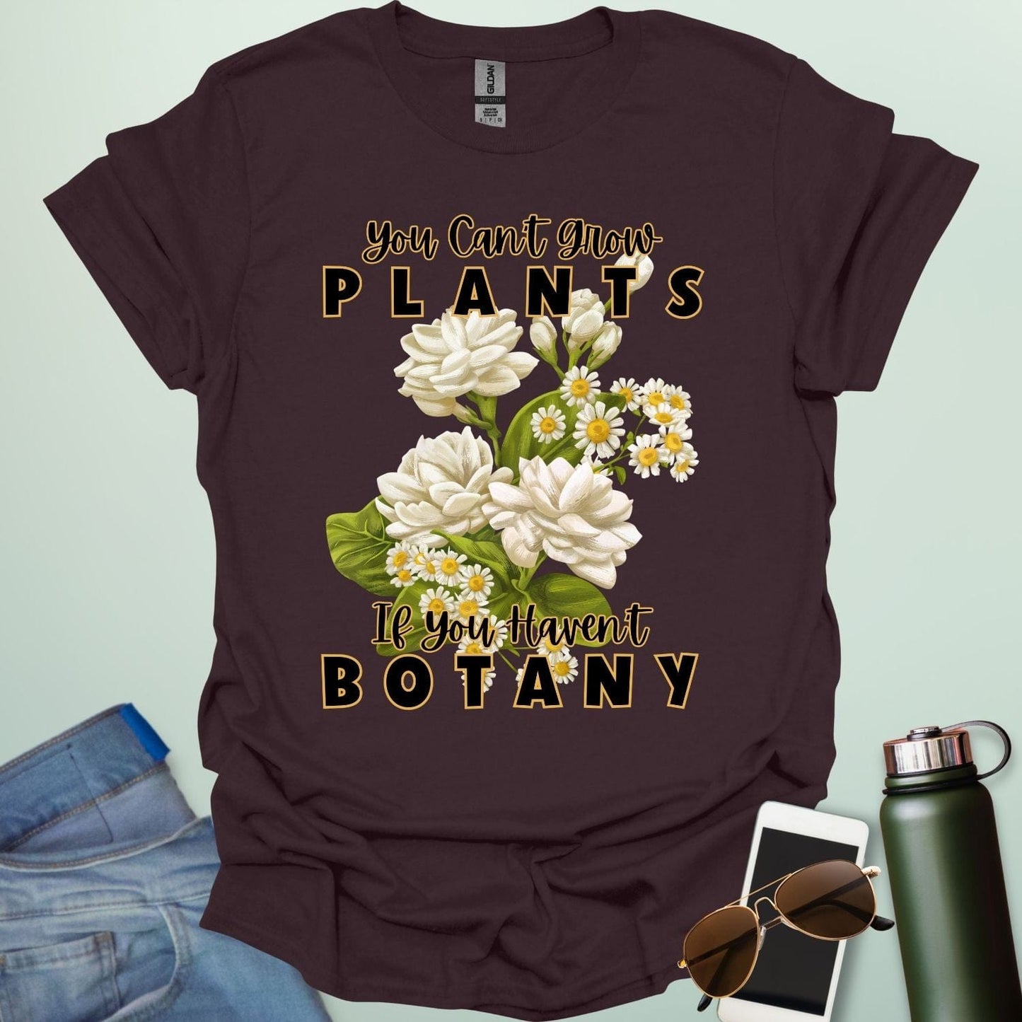 A charming t-shirt with a floral design and the text 'You Can't Grow Plants If You Haven't Botany,' a witty pun for botanists and gardeners.