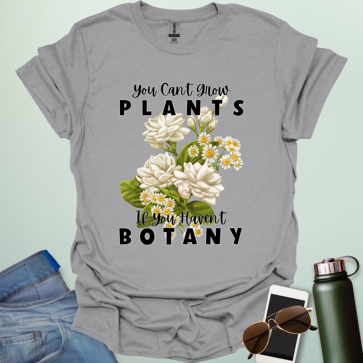 A charming t-shirt with a floral design and the text 'You Can't Grow Plants If You Haven't Botany,' a witty pun for botanists and gardeners.