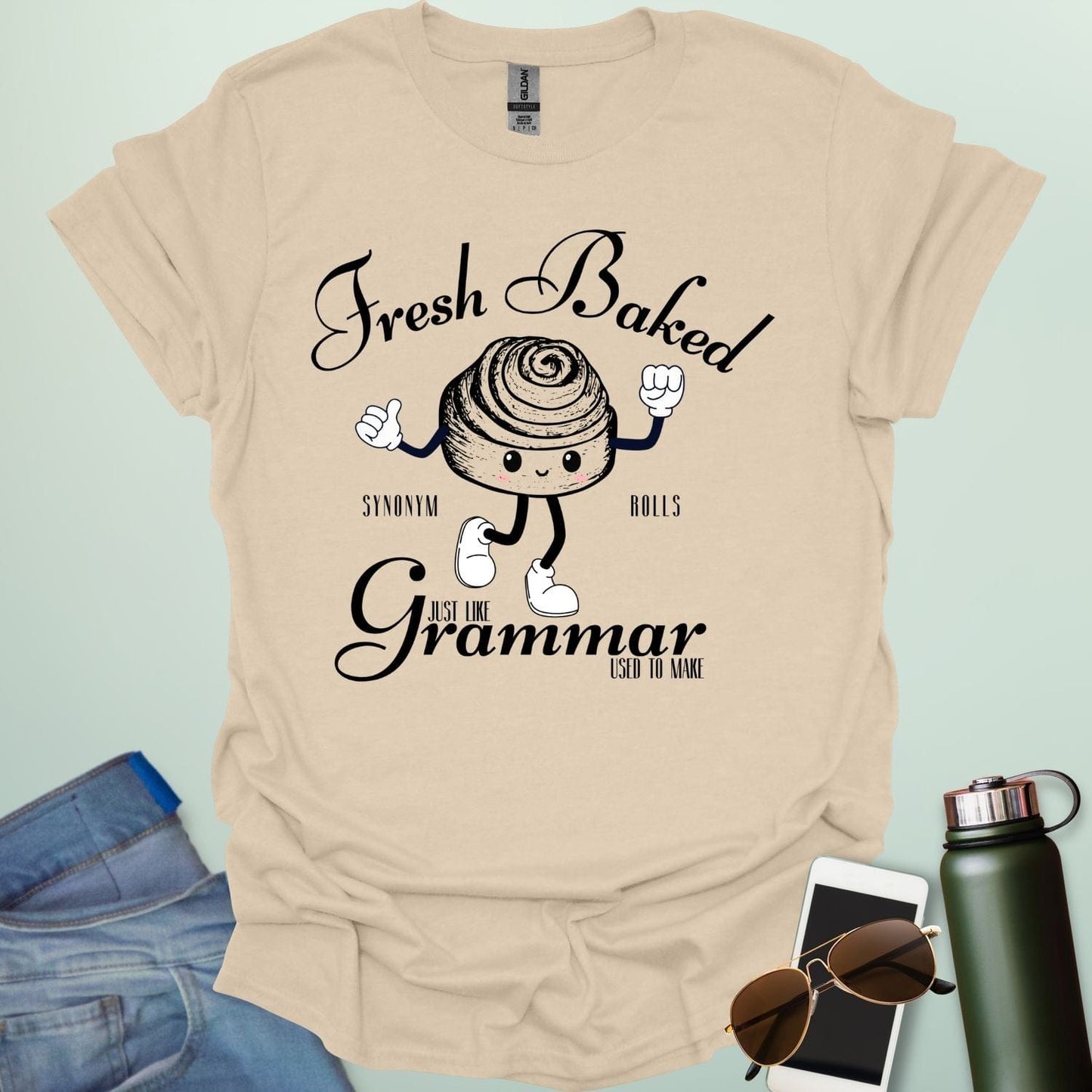 A funny t-shirt with a cute cartoon cinnamon roll and the text 'Fresh Baked Synonym Rolls Just Like Grammar Used to Make.'