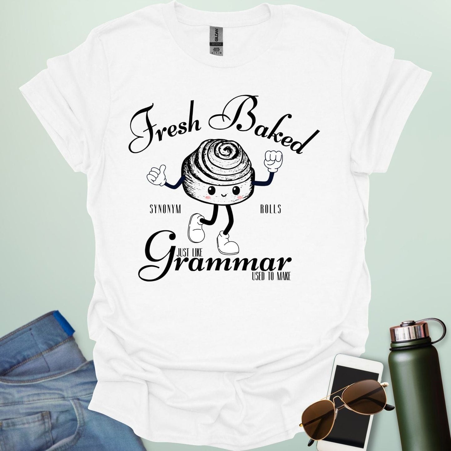 A funny t-shirt with a cute cartoon cinnamon roll and the text 'Fresh Baked Synonym Rolls Just Like Grammar Used to Make.'