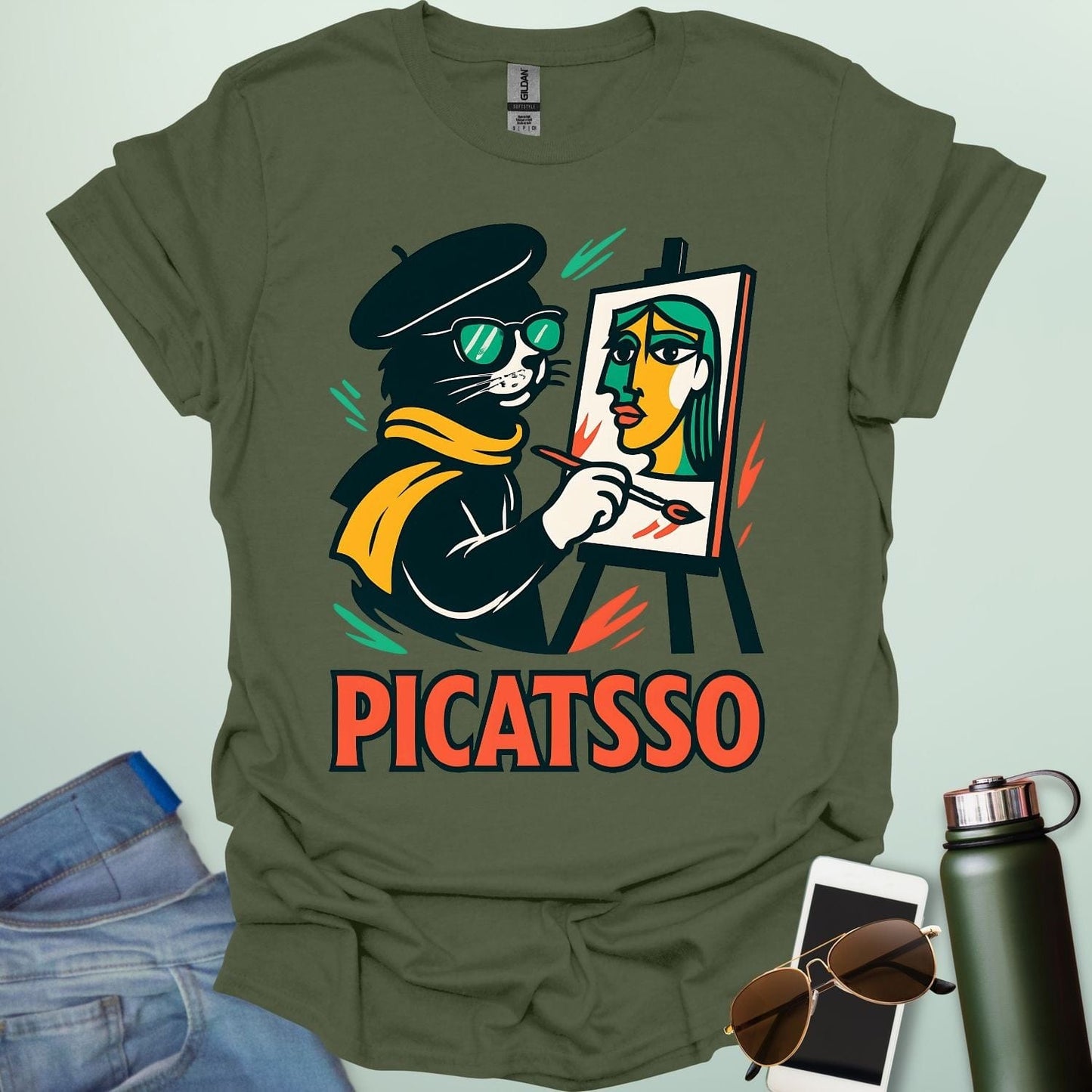 A military green t-shirt with a cartoon of a cat painting a Picasso-style portrait on an easel and the text 'PICATSSO' below.