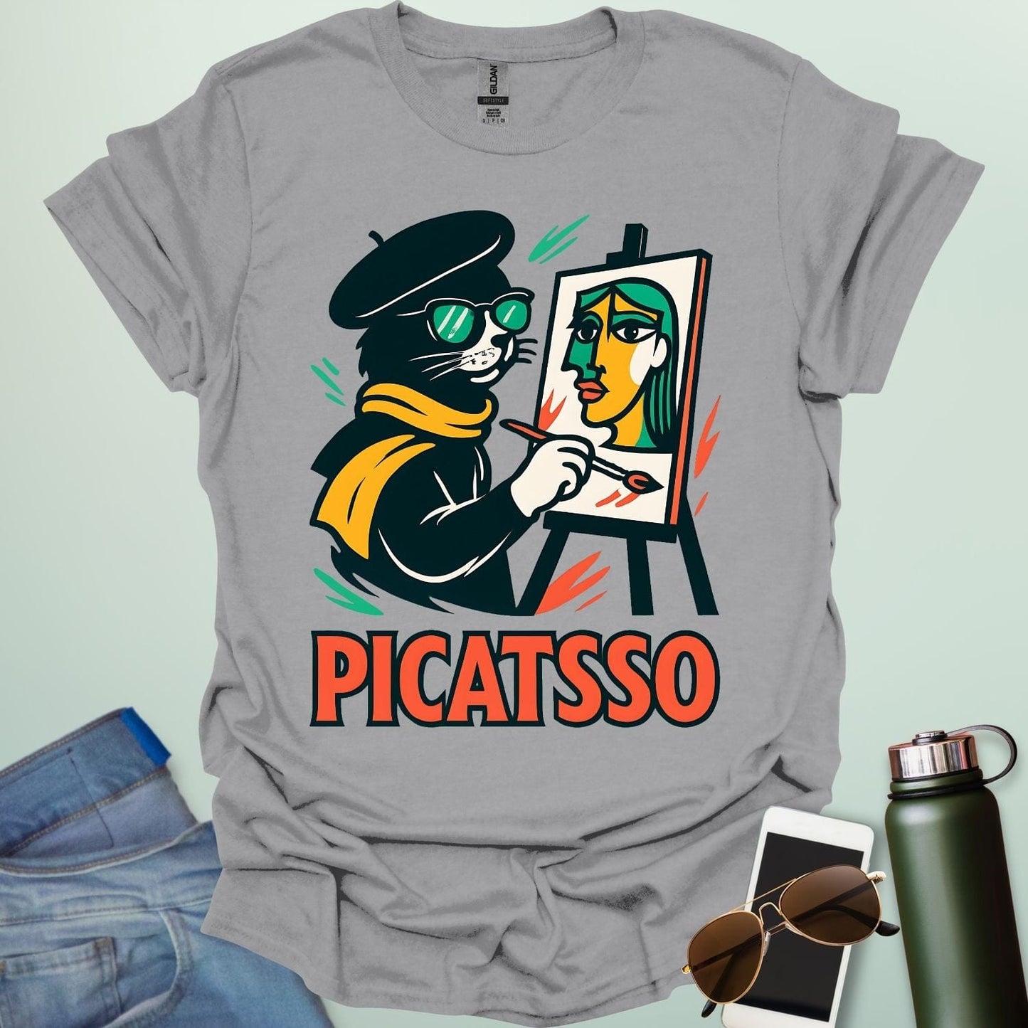 A sport grey t-shirt with a cartoon of a cat painting a Picasso-style portrait on an easel and the text 'PICATSSO' below.