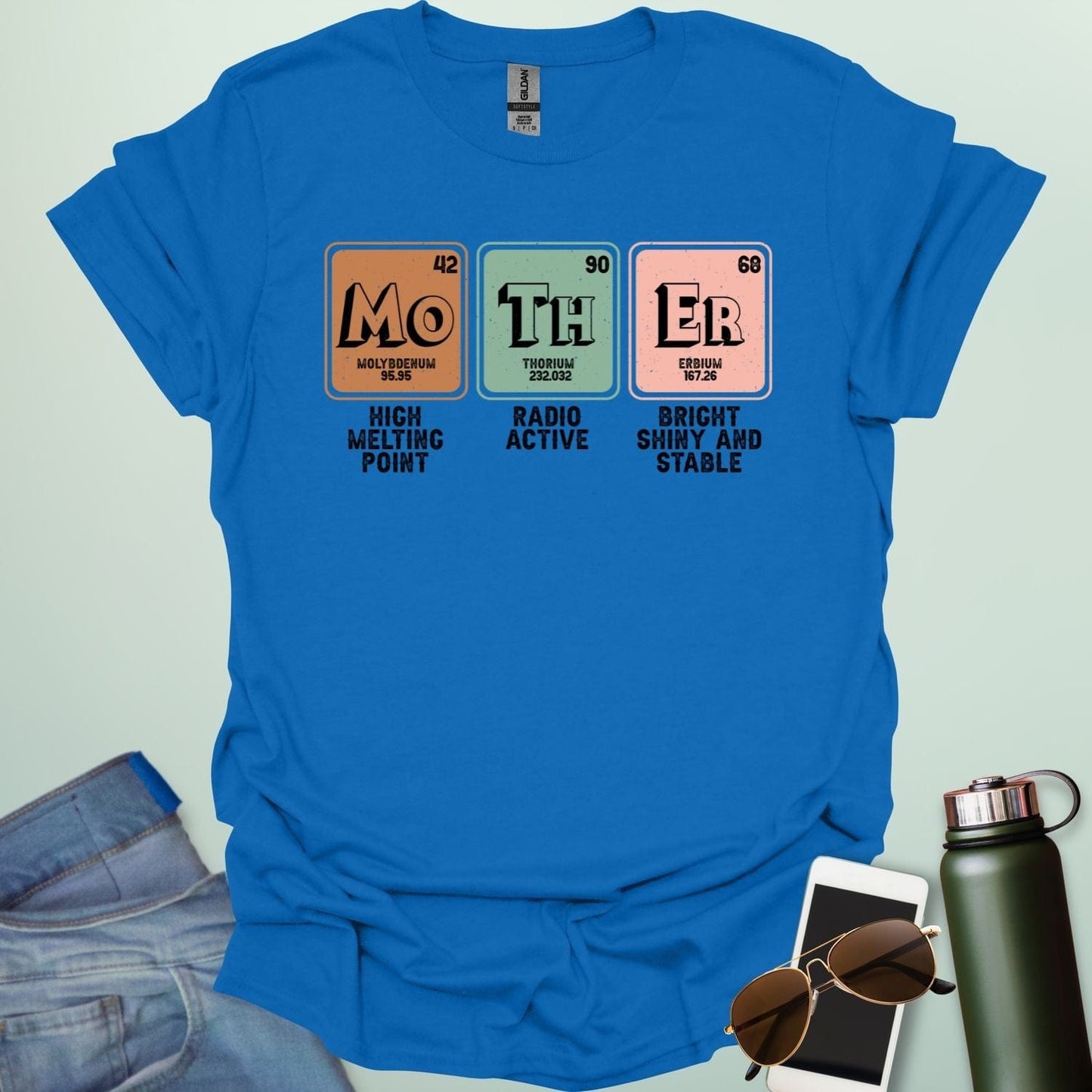 A royal blue t-shirt design with three periodic table elements: Mo (Molybdenum), Th (Thorium), and Er (Erbium), with humorous descriptions underneath.