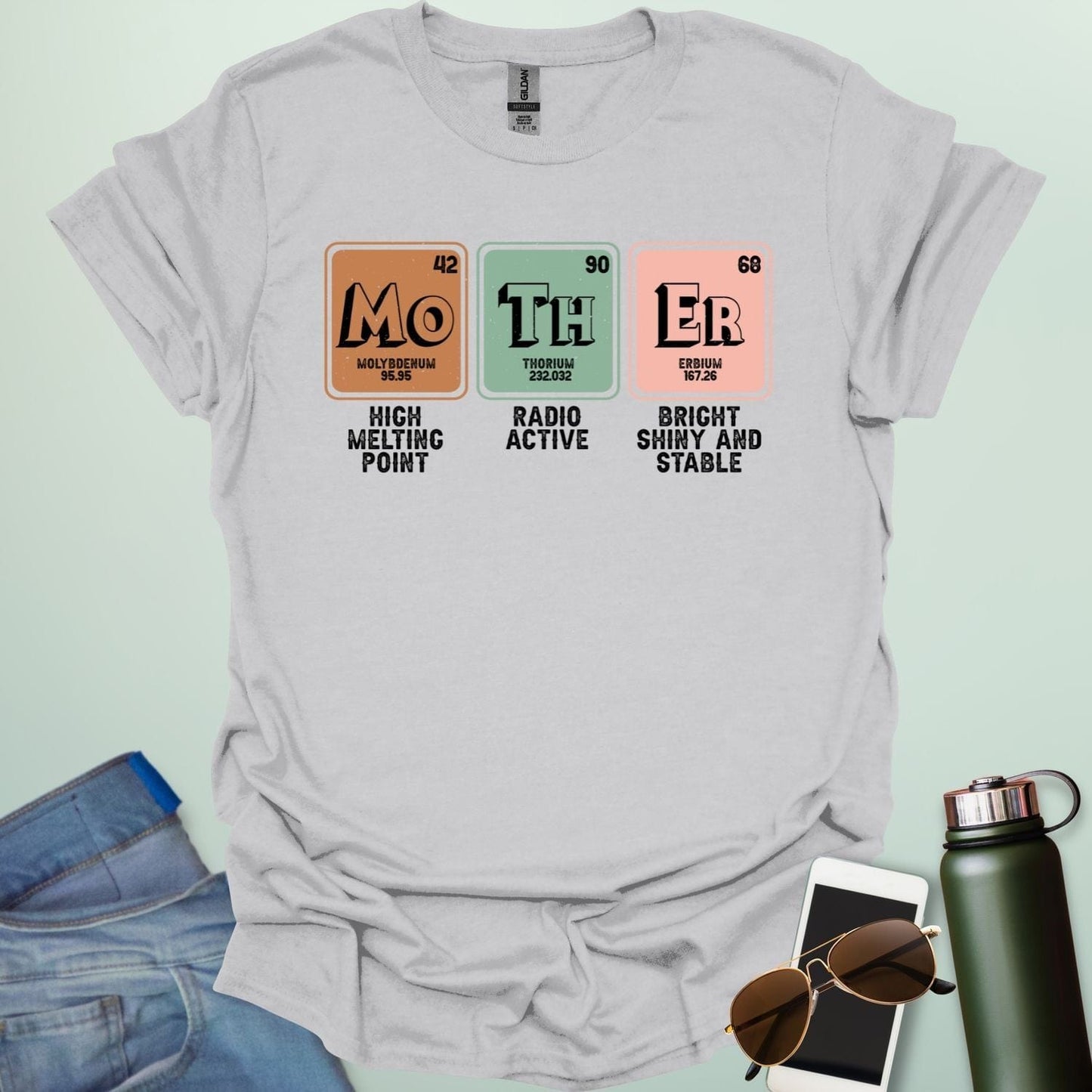 A ice grey t-shirt design with three periodic table elements: Mo (Molybdenum), Th (Thorium), and Er (Erbium), with humorous descriptions underneath.