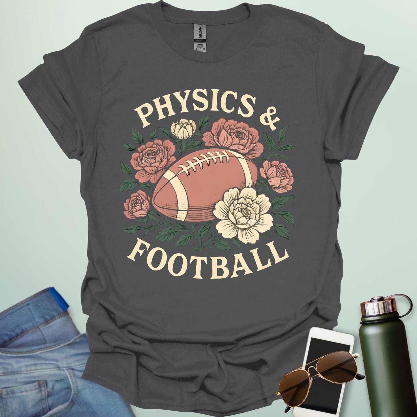 A charcoal grey t-shirt with a vintage illustration of a football surrounded by flowers and the text 'PHYSICS & FOOTBALL.'