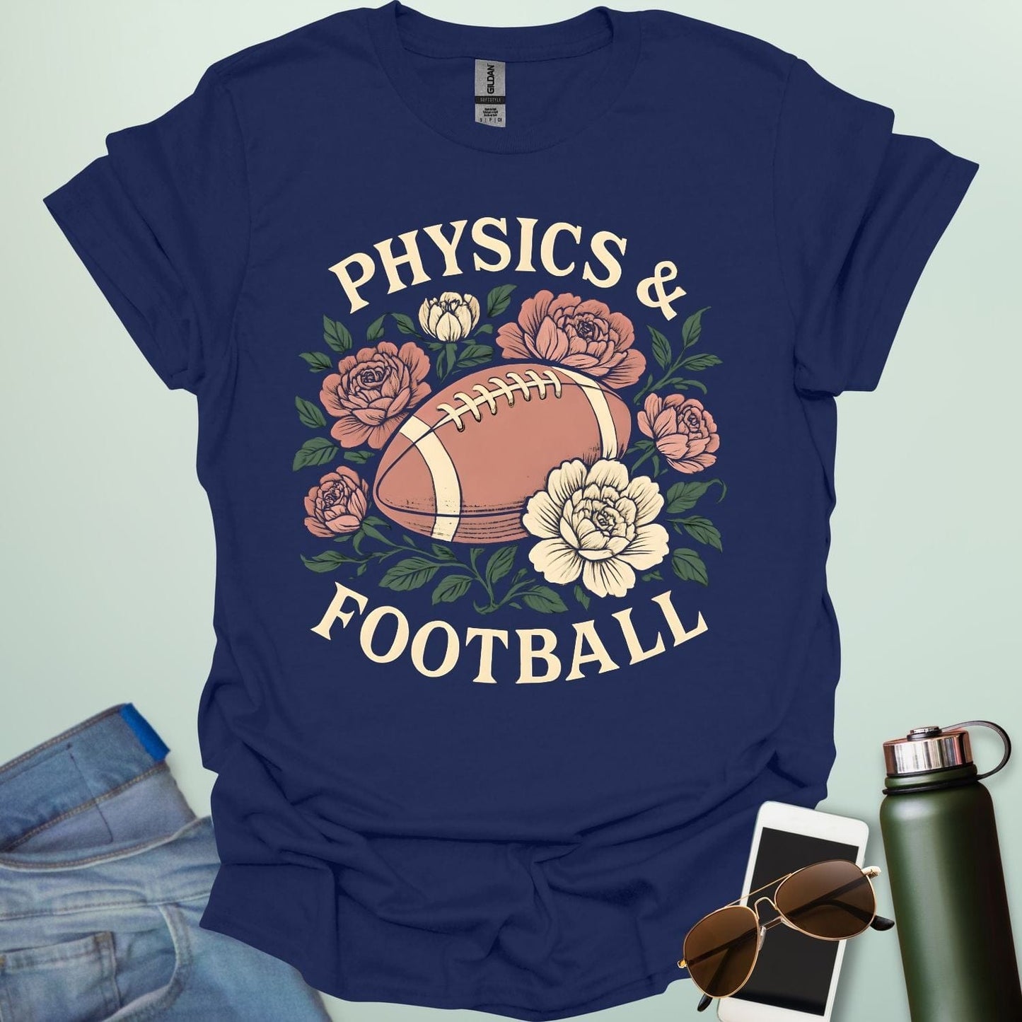 A navy blue t-shirt with a vintage illustration of a football surrounded by flowers and the text 'PHYSICS & FOOTBALL.'