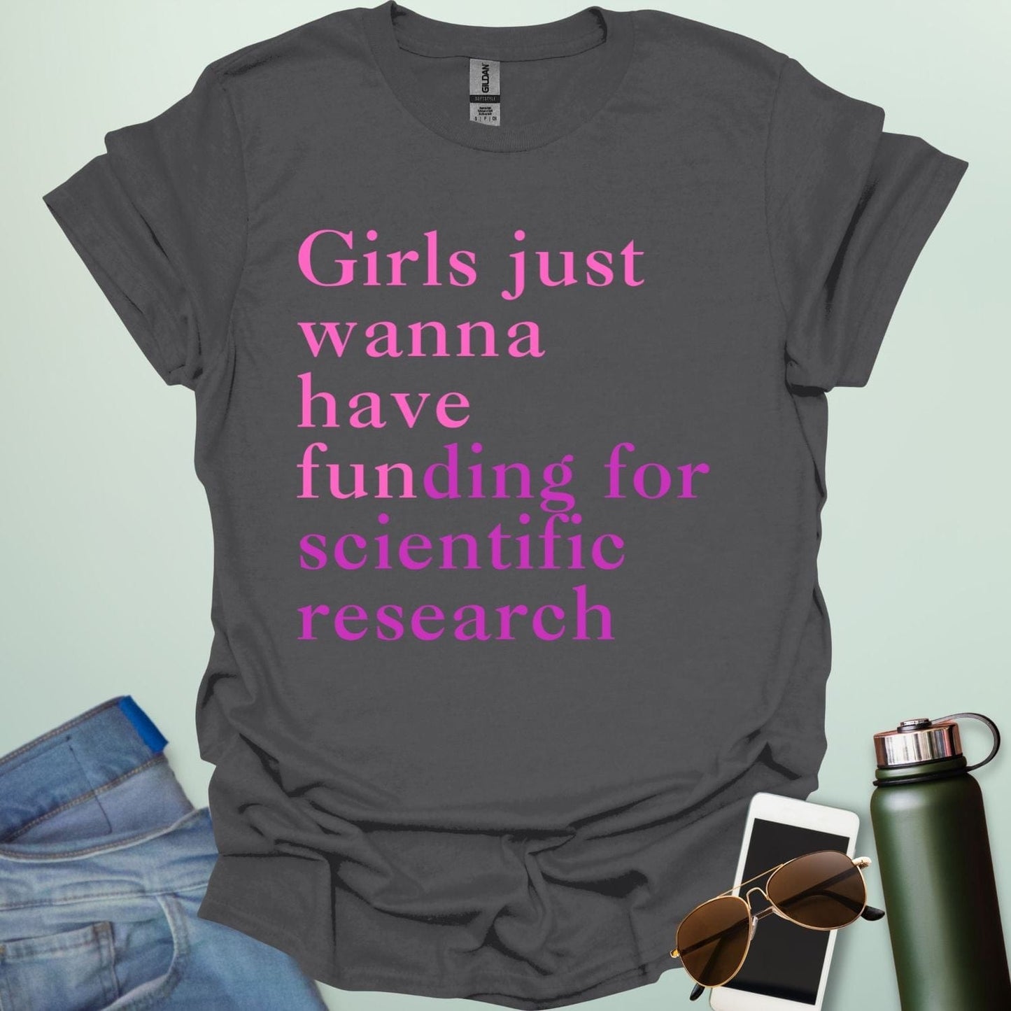 A charcoal grey t-shirt with the text 'Girls just wanna have funding for scientific research' in a pink serif font.