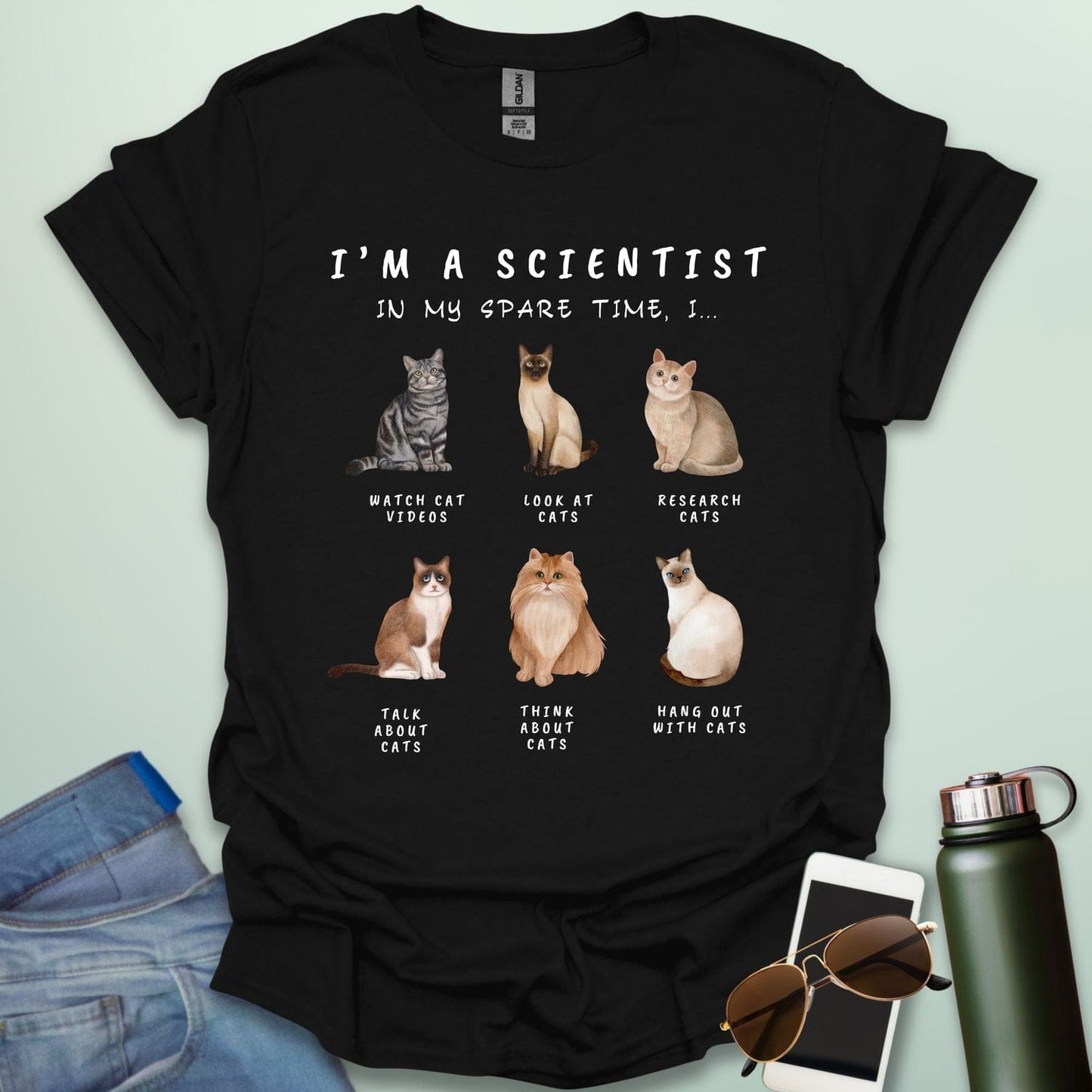 Black t-shirt with cat-themed text and illustrations on a light green background