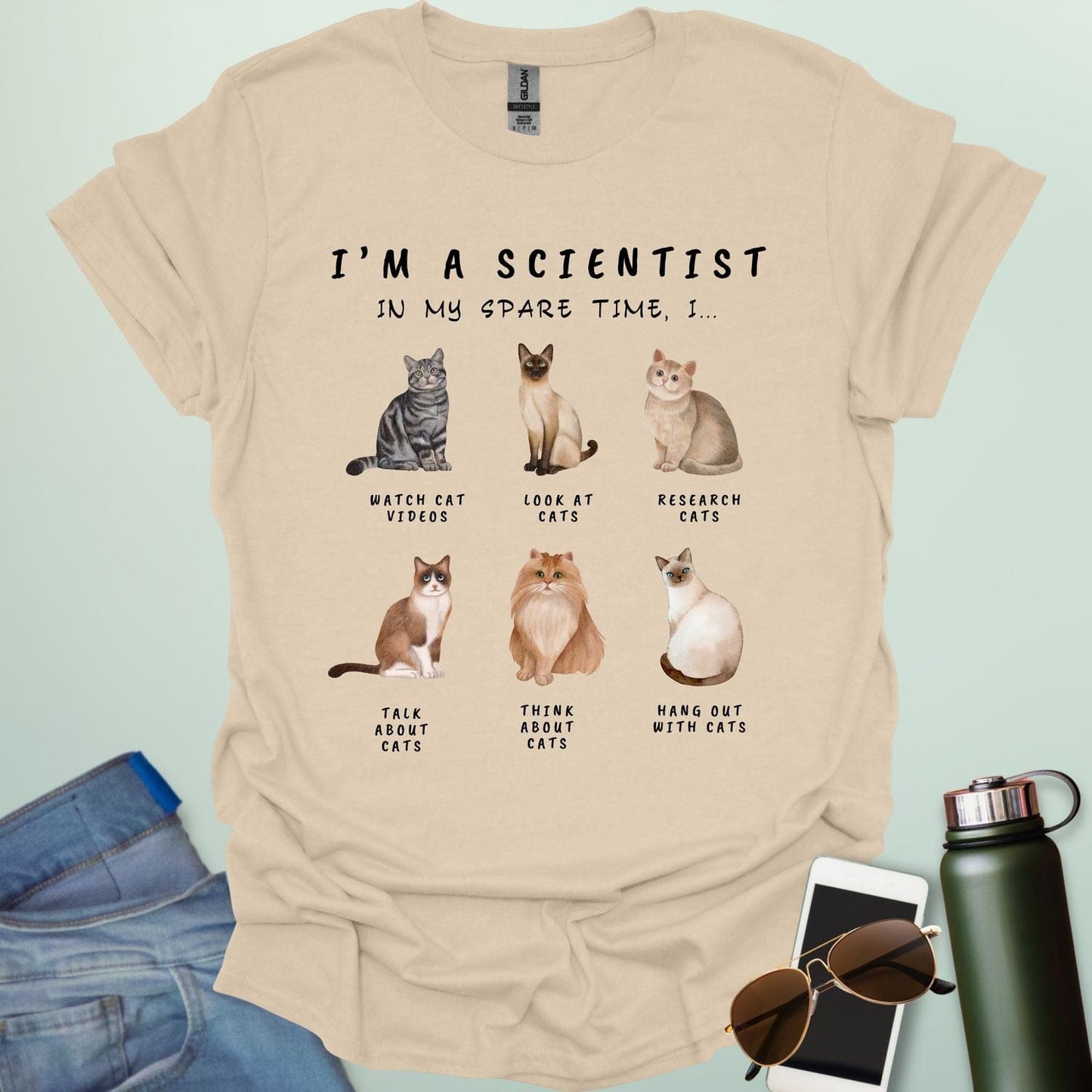 Sand t-shirt with cat-themed text and illustrations on a light blue background