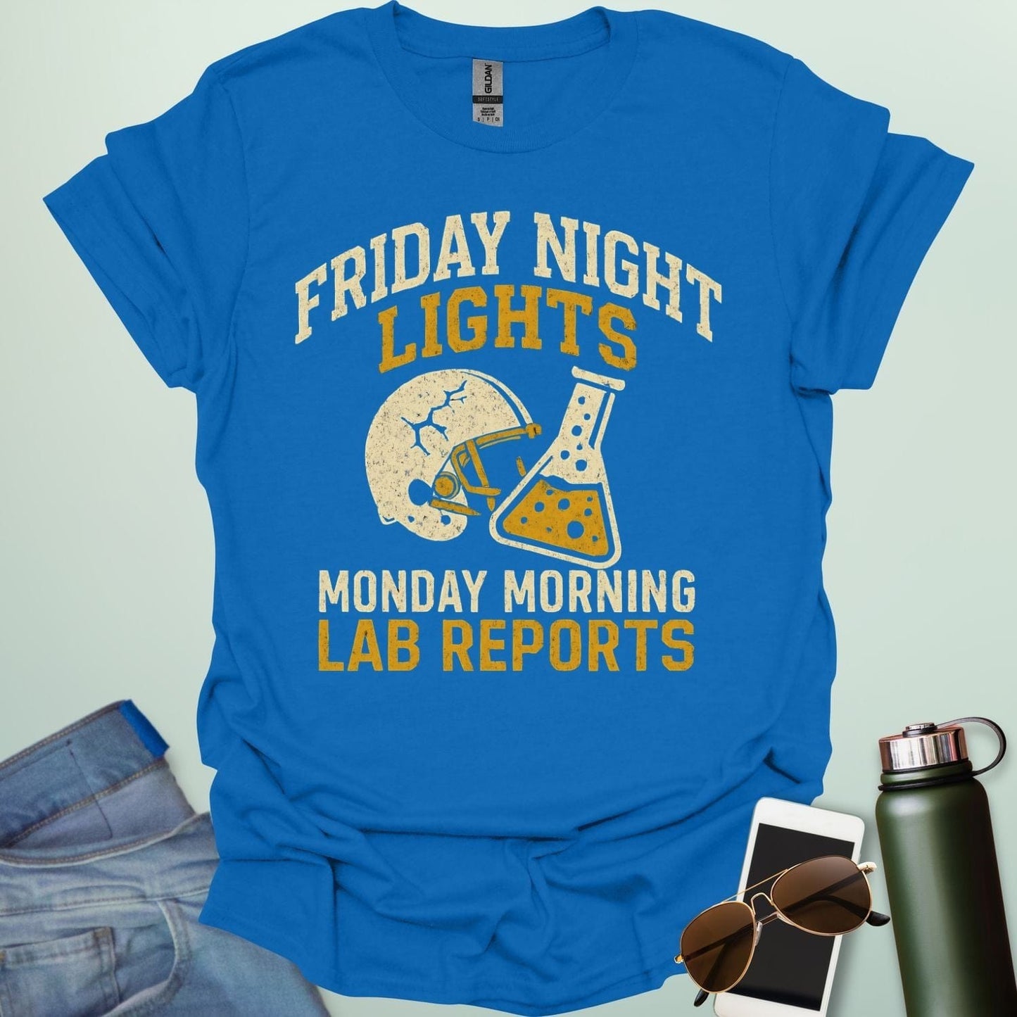 A royal blue t-shirt with a vintage football helmet and a cracked lab flask, with the text 'FRIDAY NIGHT LIGHTS' and 'MONDAY MORNING LAB REPORTS.'