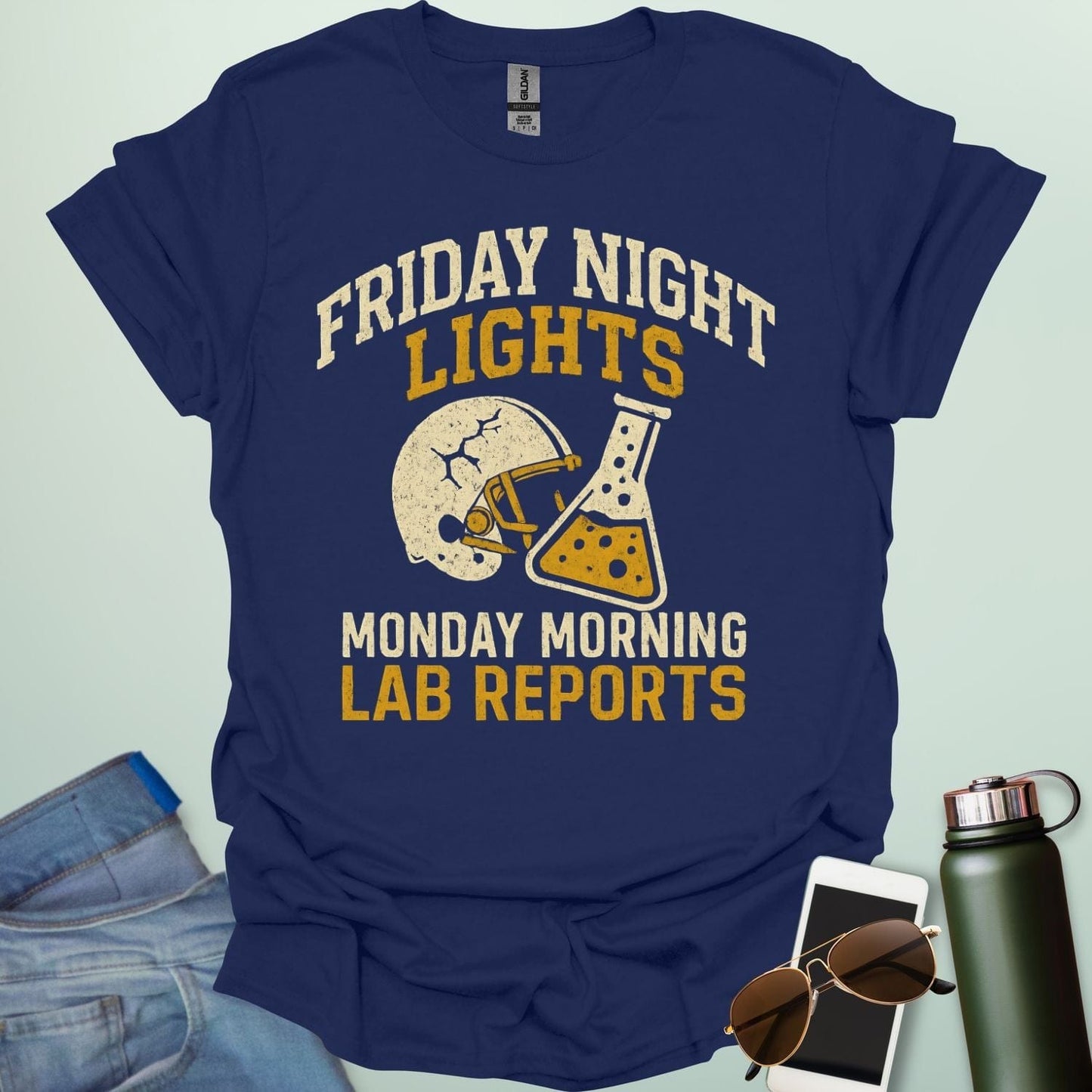 A navy blue t-shirt with a vintage football helmet and a cracked lab flask, with the text 'FRIDAY NIGHT LIGHTS' and 'MONDAY MORNING LAB REPORTS.'