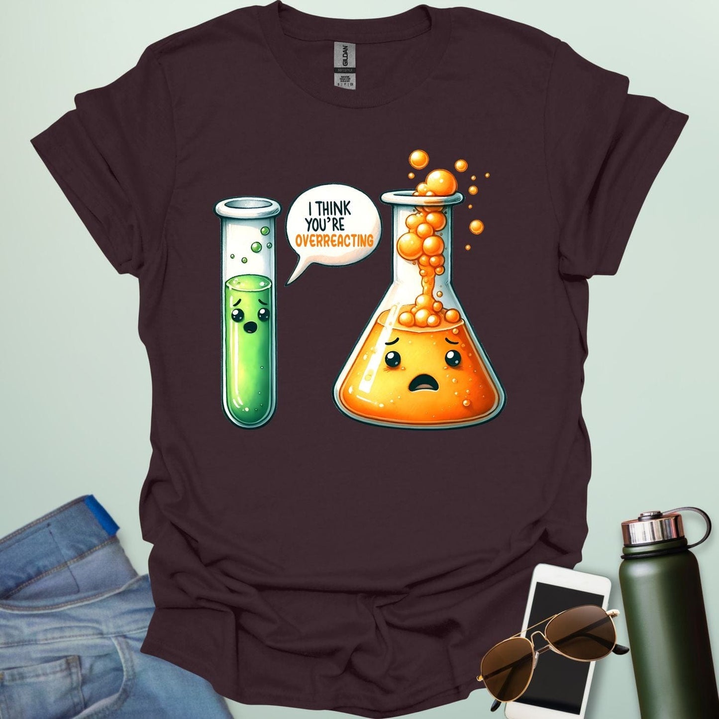Dark chocolate t-shirt with a graphic of two test tubes and a beaker on a light gray background. The test tube says, "I THINK YOU'RE OVERREACTING"
