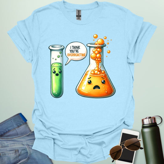 Light blue t-shirt with a graphic of two test tubes and a beaker on a light gray background. The test tube says, "I THINK YOU'RE OVERREACTING"