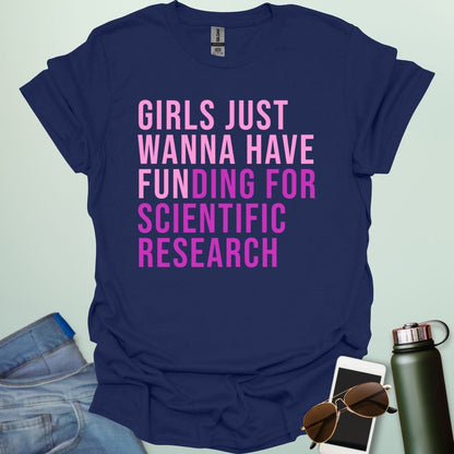 A navy blue t-shirt with the phrase 'Girls just wanna have funding for scientific research' in a bold, pink sans-serif font.