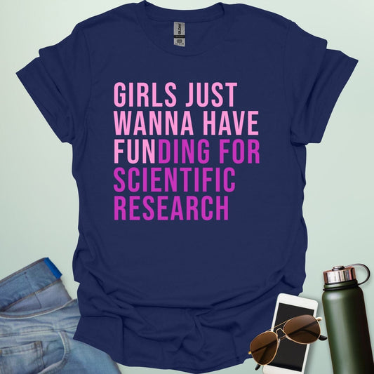 A navy blue t-shirt with the phrase 'Girls just wanna have funding for scientific research' in a bold, pink sans-serif font.