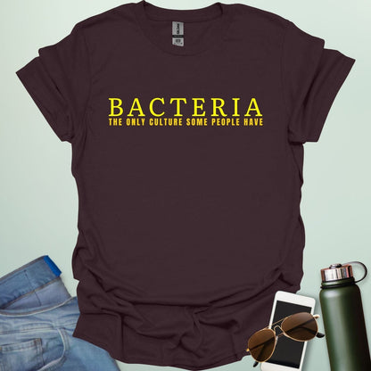 A dark chocolate t-shirt with the text 'BACTERIA THE ONLY CULTURE SOME PEOPLE HAVE' in yellow, bold font.