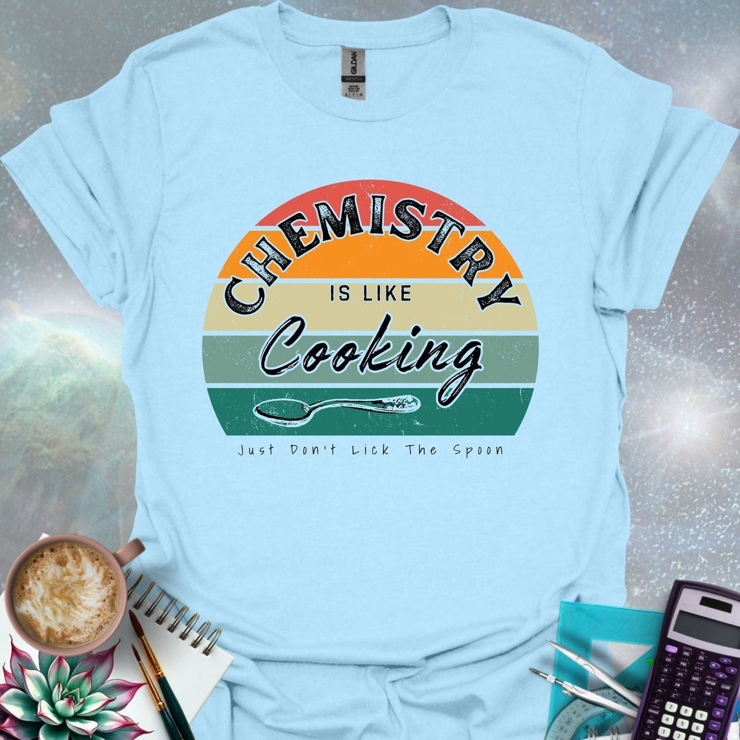 The text 'Chemistry is like Cooking - Just don't lick the spoon' in a distressed, grunge font, with a spoon graphic and a retro-style sunset background.